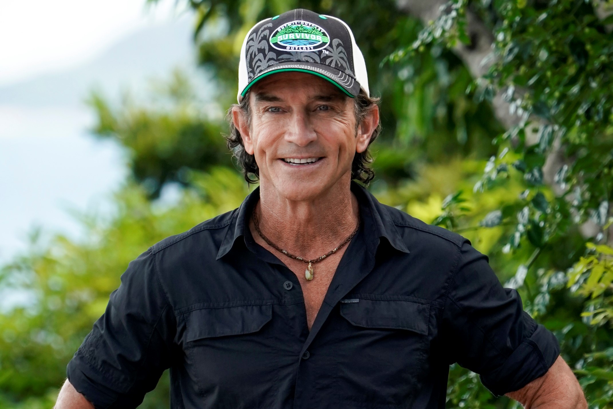 Jeff Probst, who announces the twists during 'Survivor' Season 42, wears a black button-up shirt and a black, white, and green 'Survivor' baseball cap.