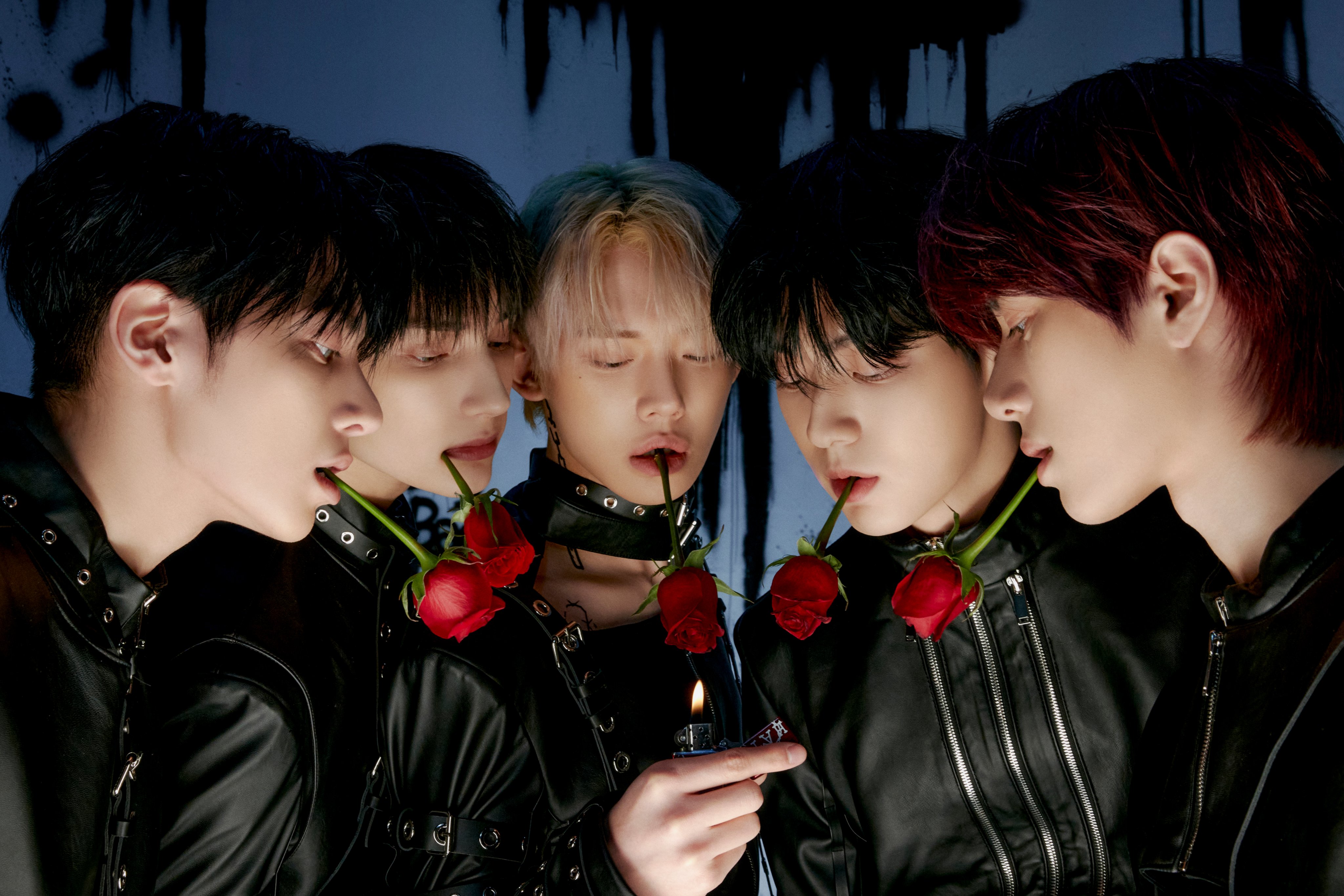 The members of TXT stand together with roses in their mouths