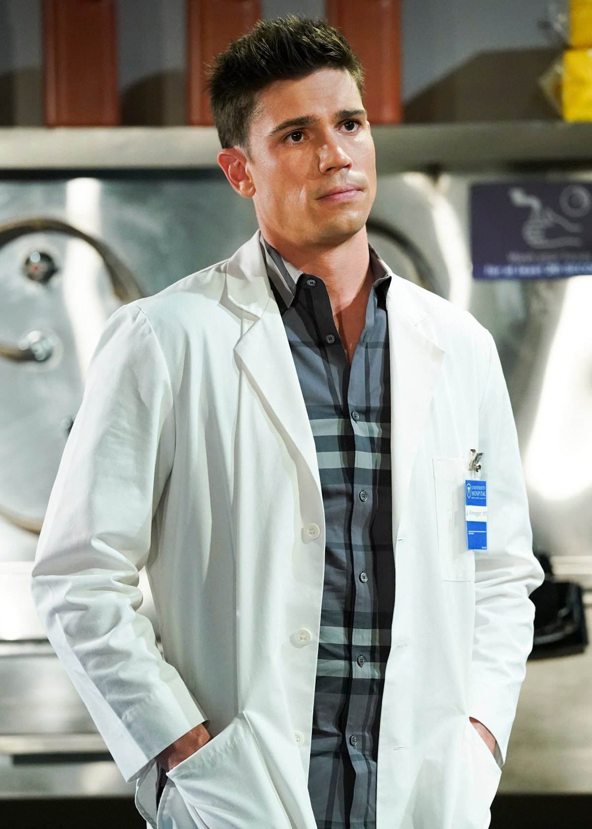 'The Bold and the Beautiful' actor Tanner Novlan wearing a plaid shirt and white lab coat in a scene from the soap opera.
