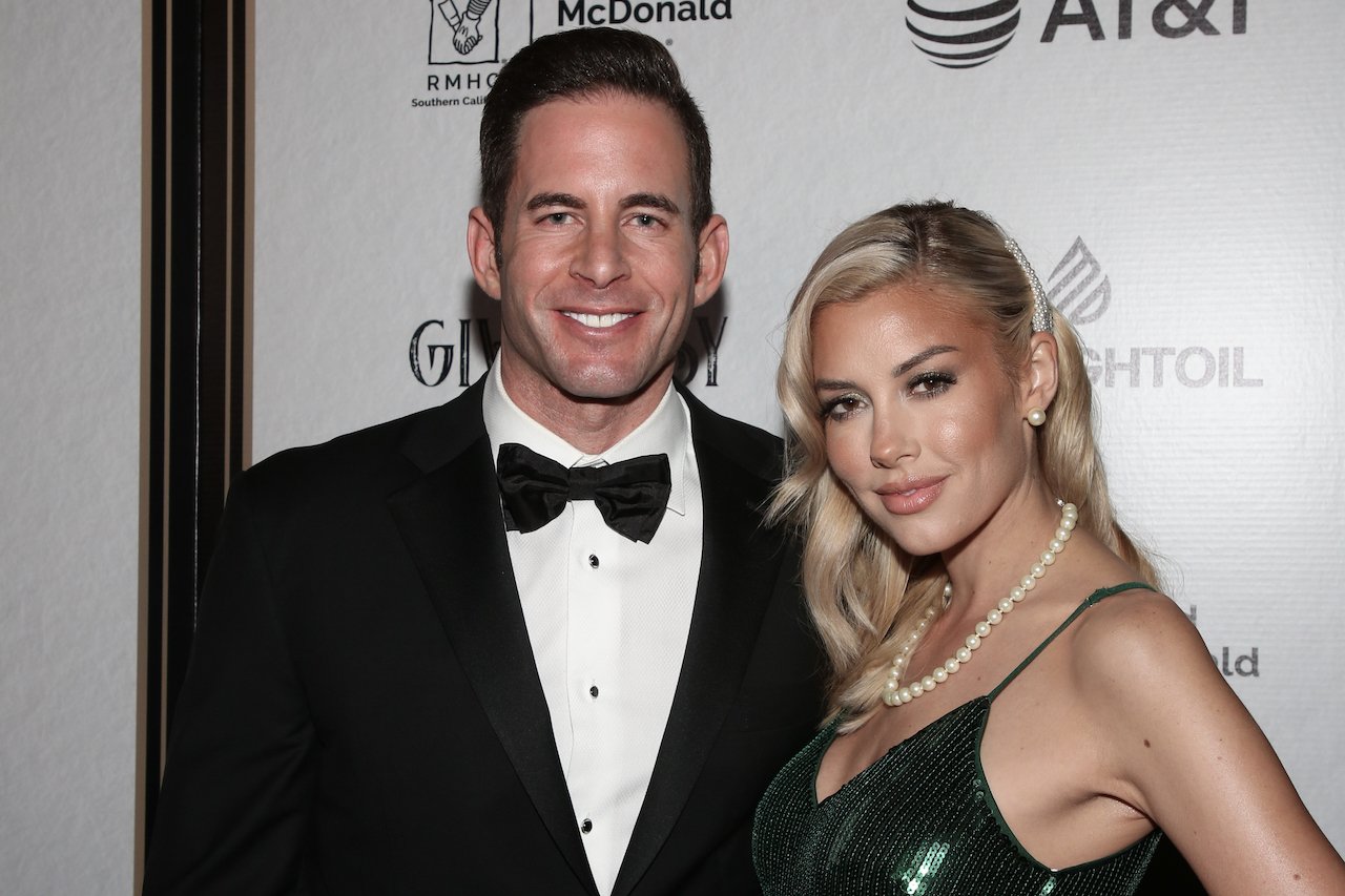 Tarek El Moussa wears a tux and Heather Rae Young wears a black dress on the red carpet.