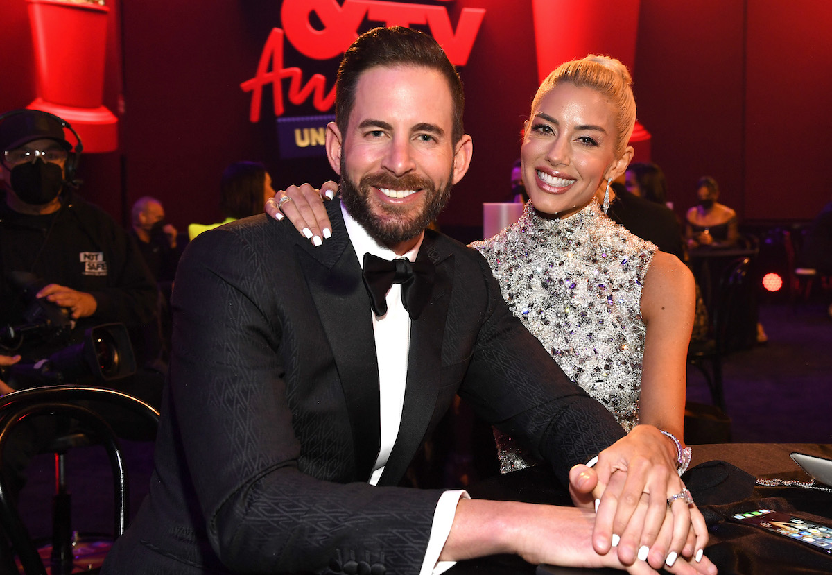 Tarek El Moussa and Heather Rae Young smile and pose together at an event.