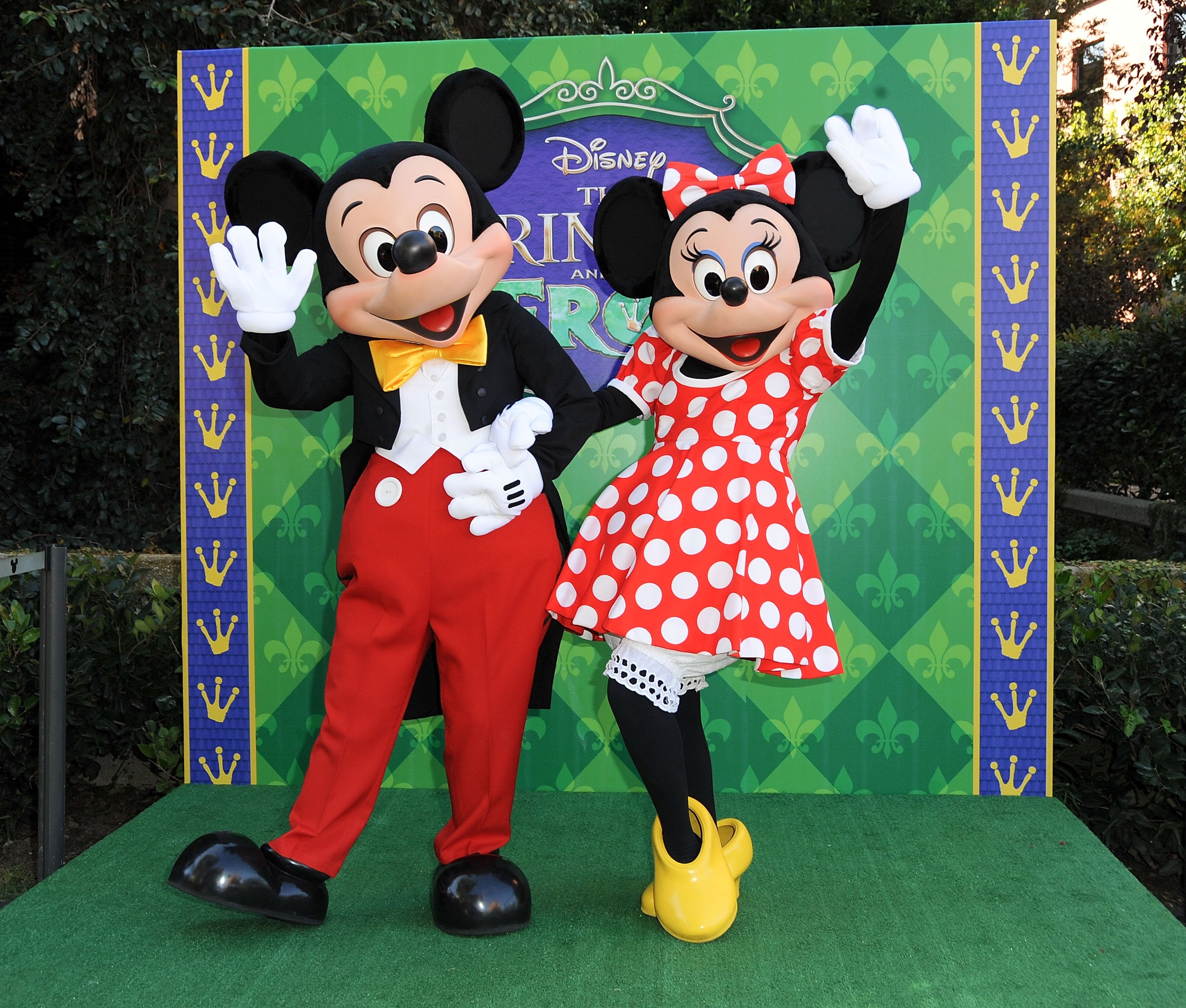 Mickey Mouse and Minnie Mouse standing in front of a green backdrop