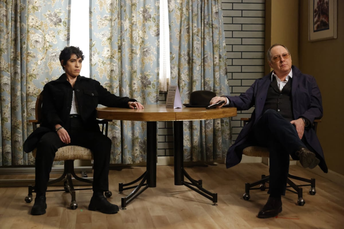 Diany Rodriguez as Weecha Xiu, James Spader as Raymond Reddington in The Blacklist Season 9. Red and Weecha sit at a table waiting.