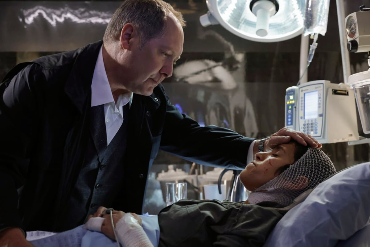 James Spader as Raymond 'Red' Reddington and Diany Rodriguez as Weecha Xiu in The Blacklist Season 9. Weecha lays in a hospital bed. Red places his head on her forehead.  
