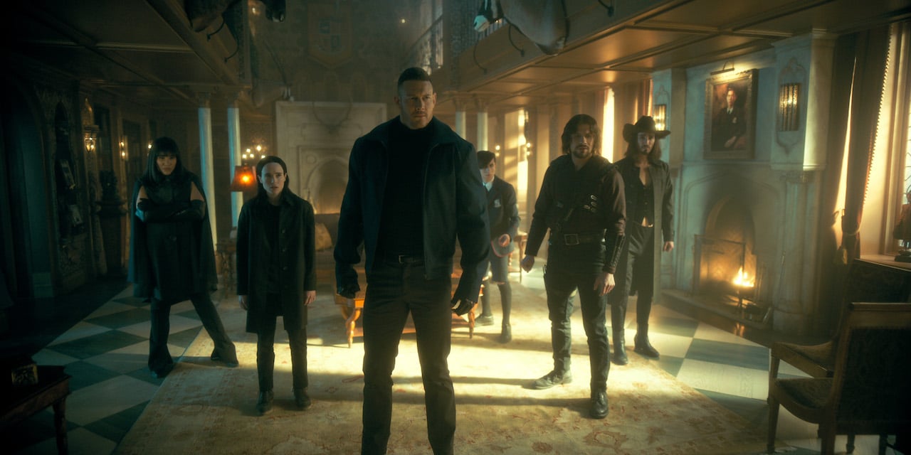 Emmy Raver-Lampman as Allison Hargreeves, Elliot Page, Tom Hopper as Luther Hargreeves, Aidan Gallagher as Number Five, David Castañeda as Diego Hargreeves, Robert Sheehan as Klaus Hargreeves stand together in the living room of their mansion on 'The Umbrella Academy'.