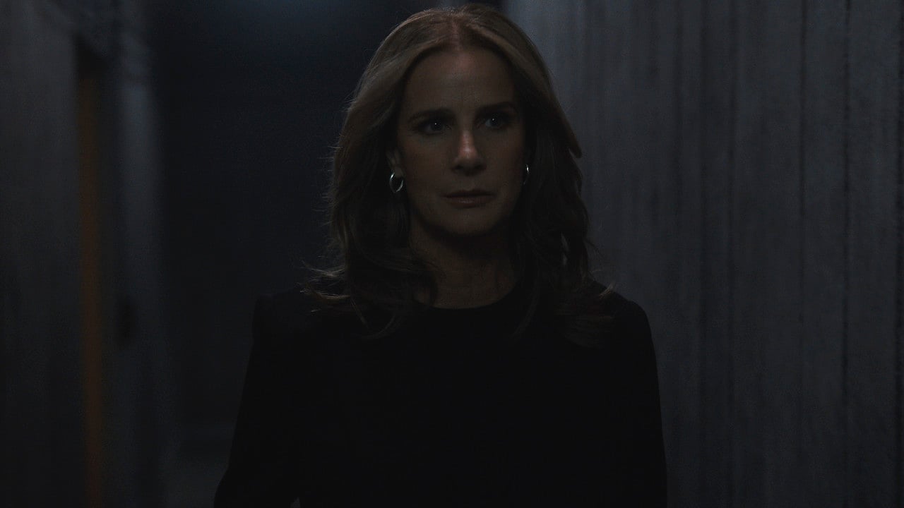 Rachel Griffiths as Gretchen Klein in 'The Wilds' stands in a dark hallway.