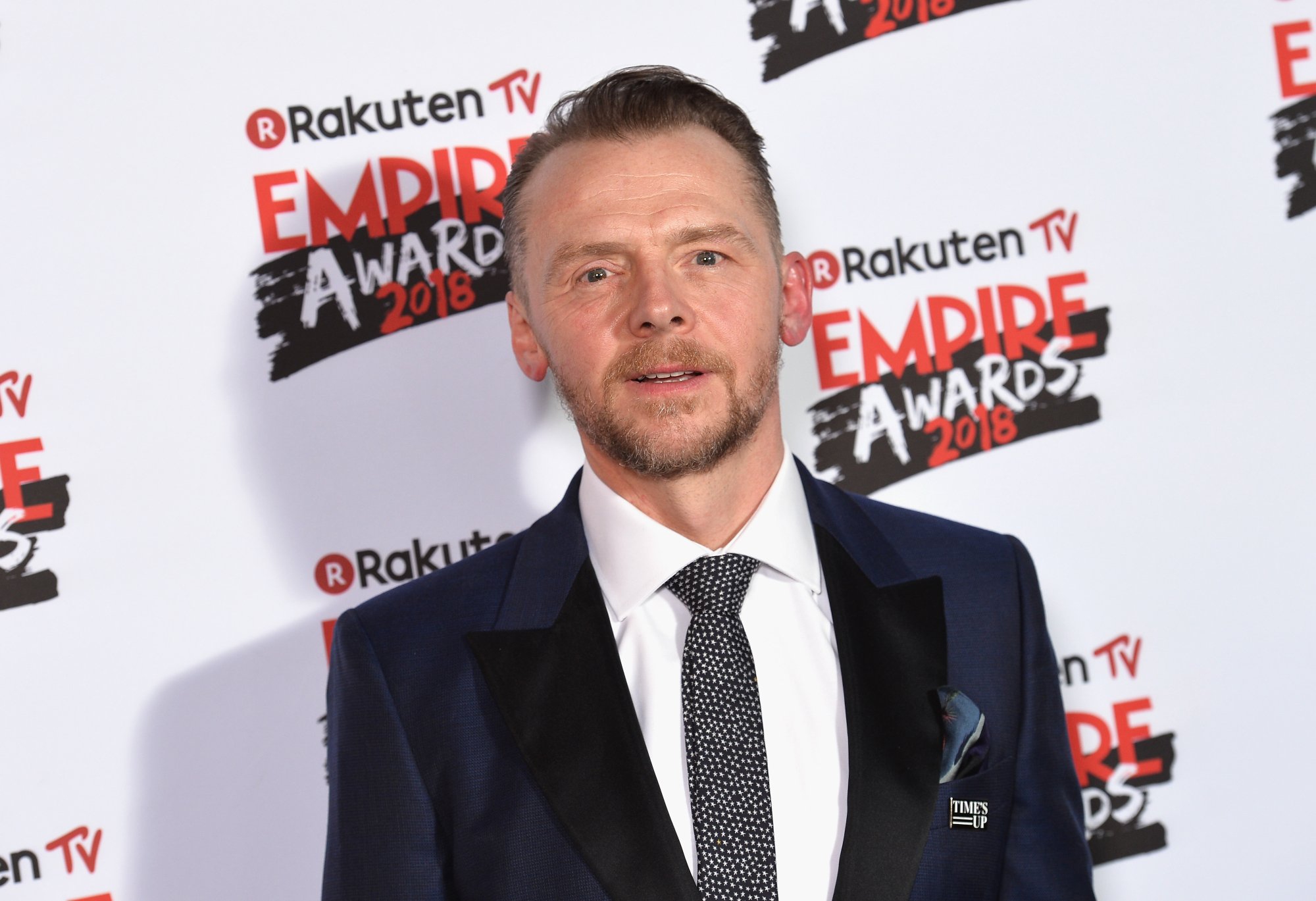 'The World's End' actor Simon Pegg wearing a suit and tie in front of a step and repeat