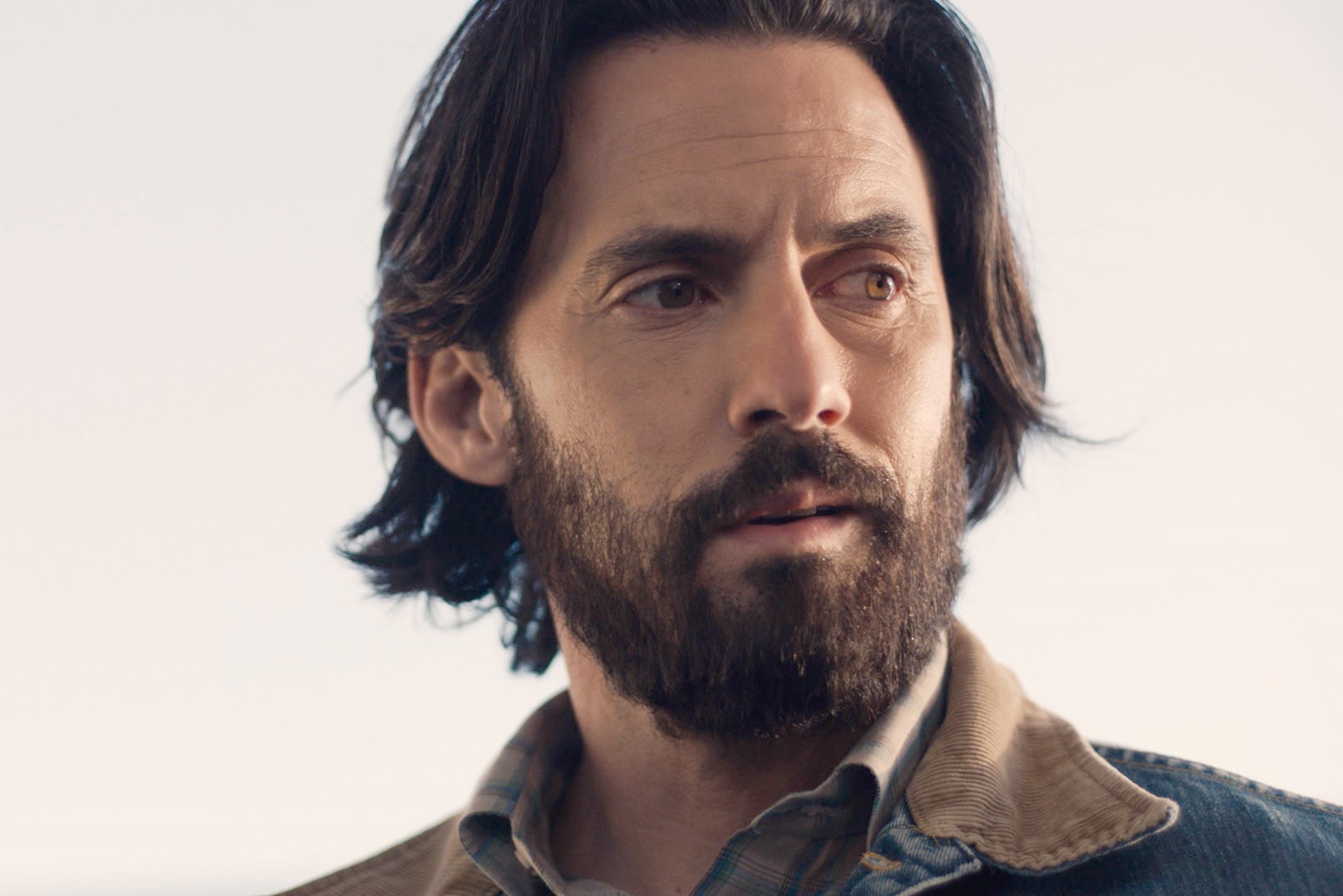 Milo Ventimiglia, in character as Jack Pearson in 'This Is Us' Season 5, wears a jean jacket over a blue and tan plaid shirt.