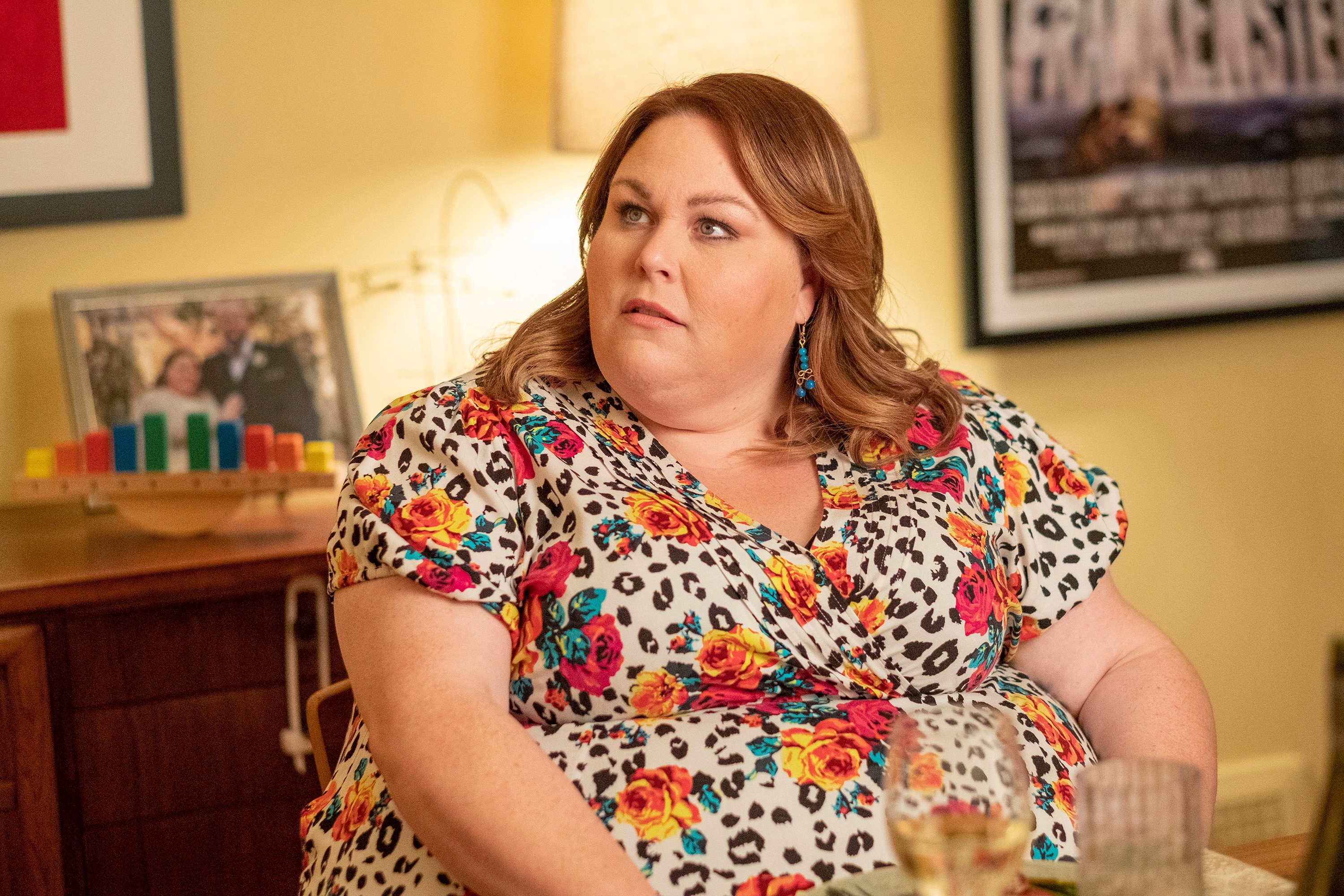 Chrissy Metz, in character as Kate in 'This Is Us' Season 6, wears a white dress with black leopard print and red and orange roses on it.