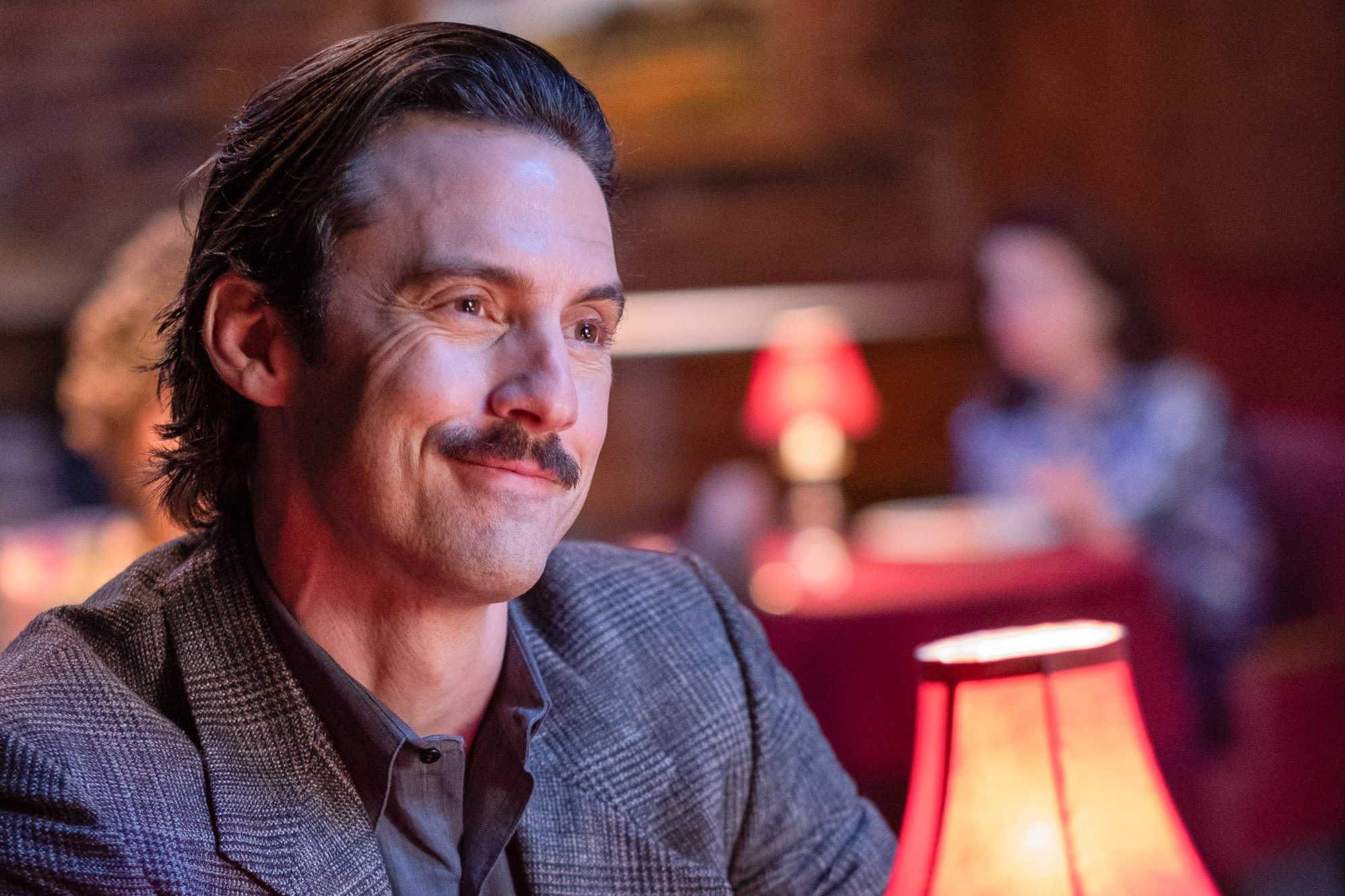 Milo Ventimiglia, in character as Jack in 'This Is Us' Season 6 Episode 13, wears a gray suit over a gray button-up shirt.