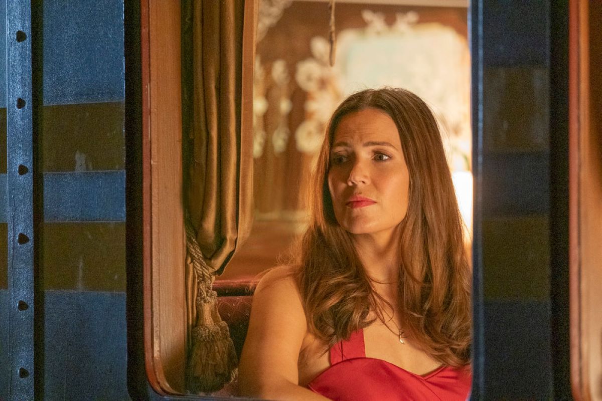 Mandy Moore, who stars as Rebecca in 'This Is Us' Season 6, wears a red dress while looking out of a train window.