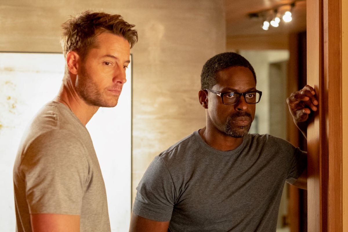 Justin Hartley and Sterling K. Brown, who play Kevin and Randall in 'This Is Us' Season 6, share a scene in the future timeline. Kevin wears a light gray shirt. Randall wears a dark gray shirt.