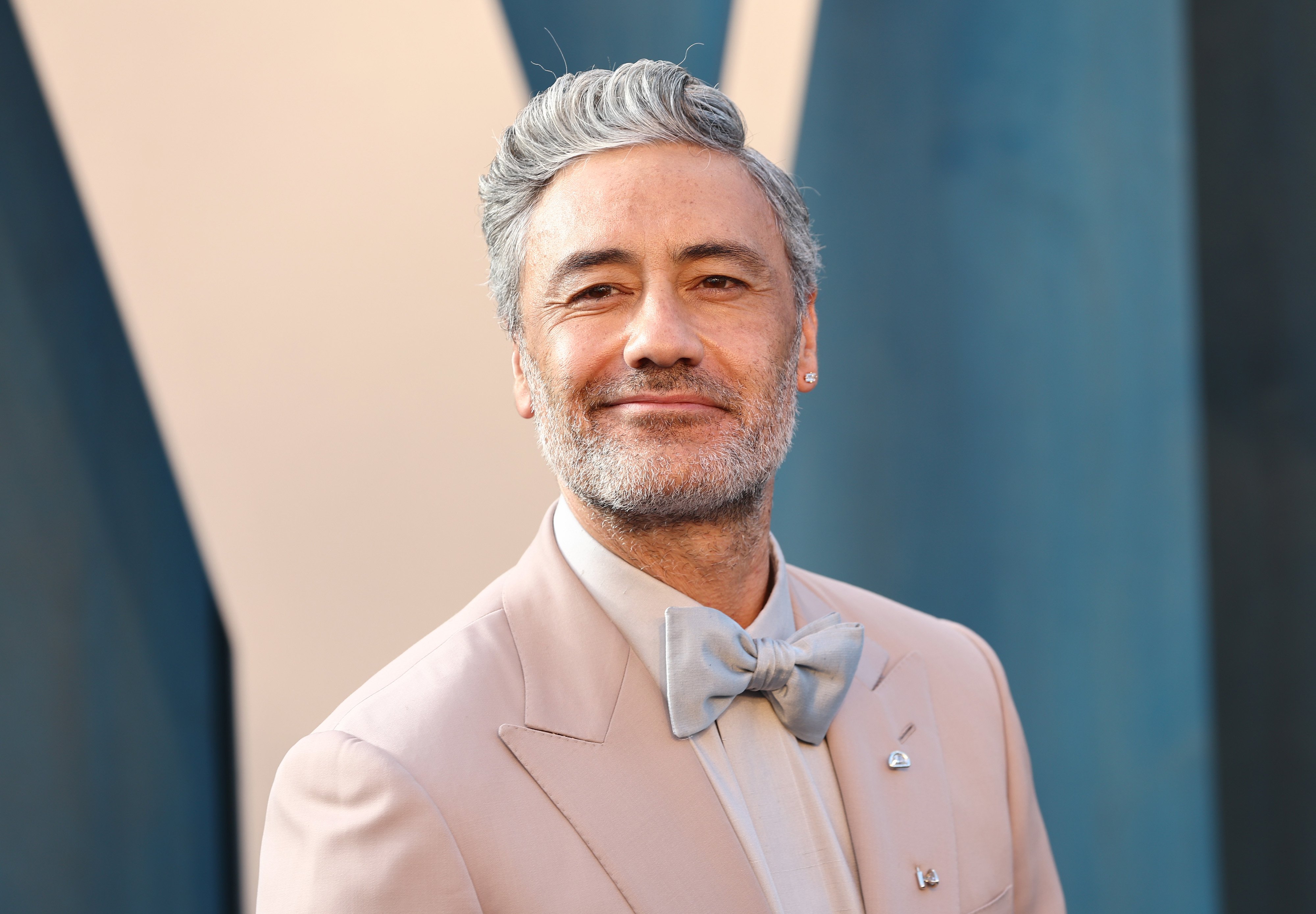 Taika Waititi, who directed 'Thor: Love and Thunder,' wears a light pink suit over a white button-up shirt and silver bow tie.