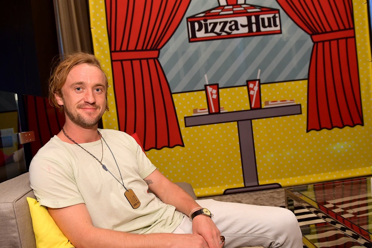 Tom Felton smiling while wearing a white t-shirt.