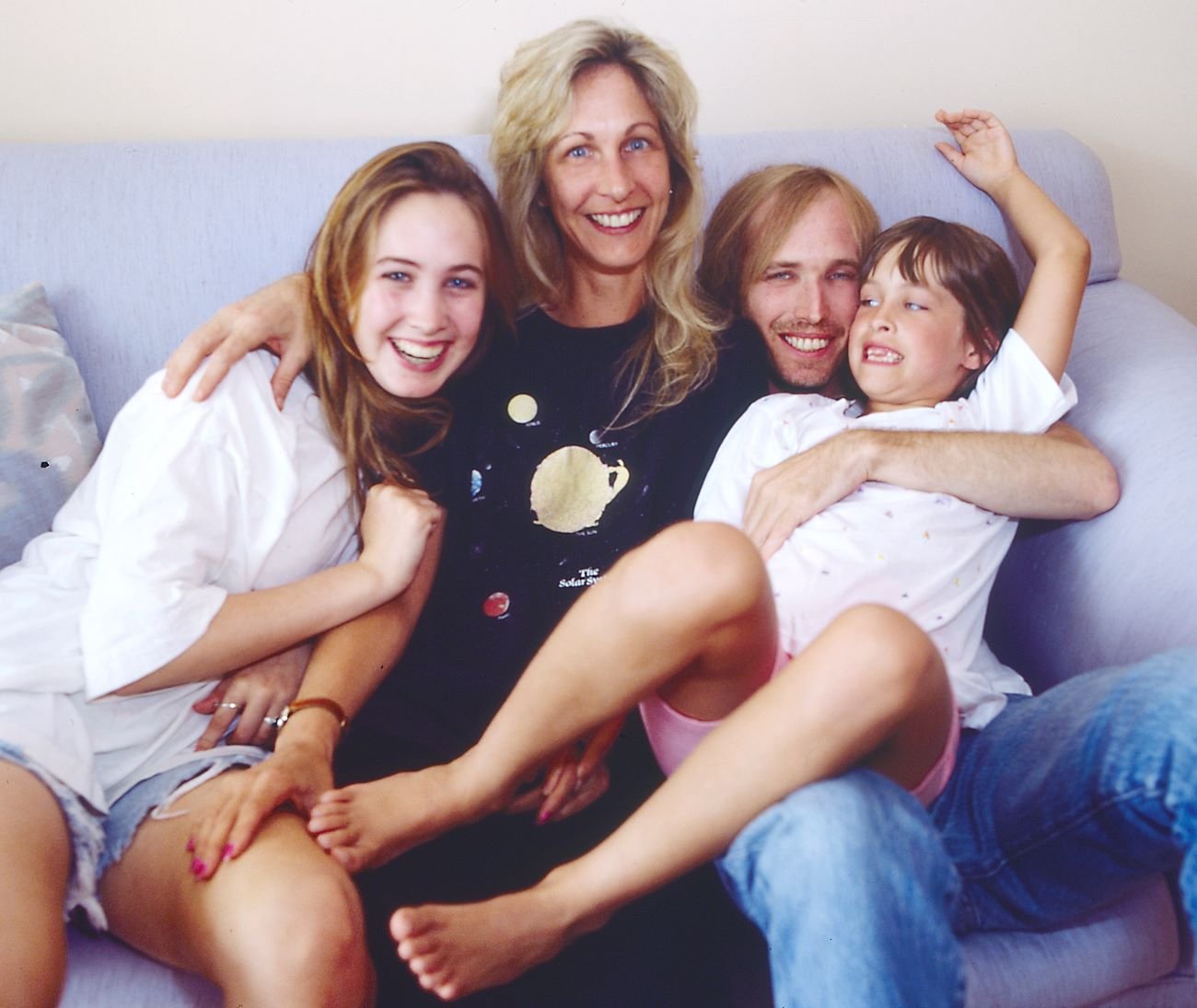 Tom Petty, Jane Benyo, and their two daughters sit on a couch together. 