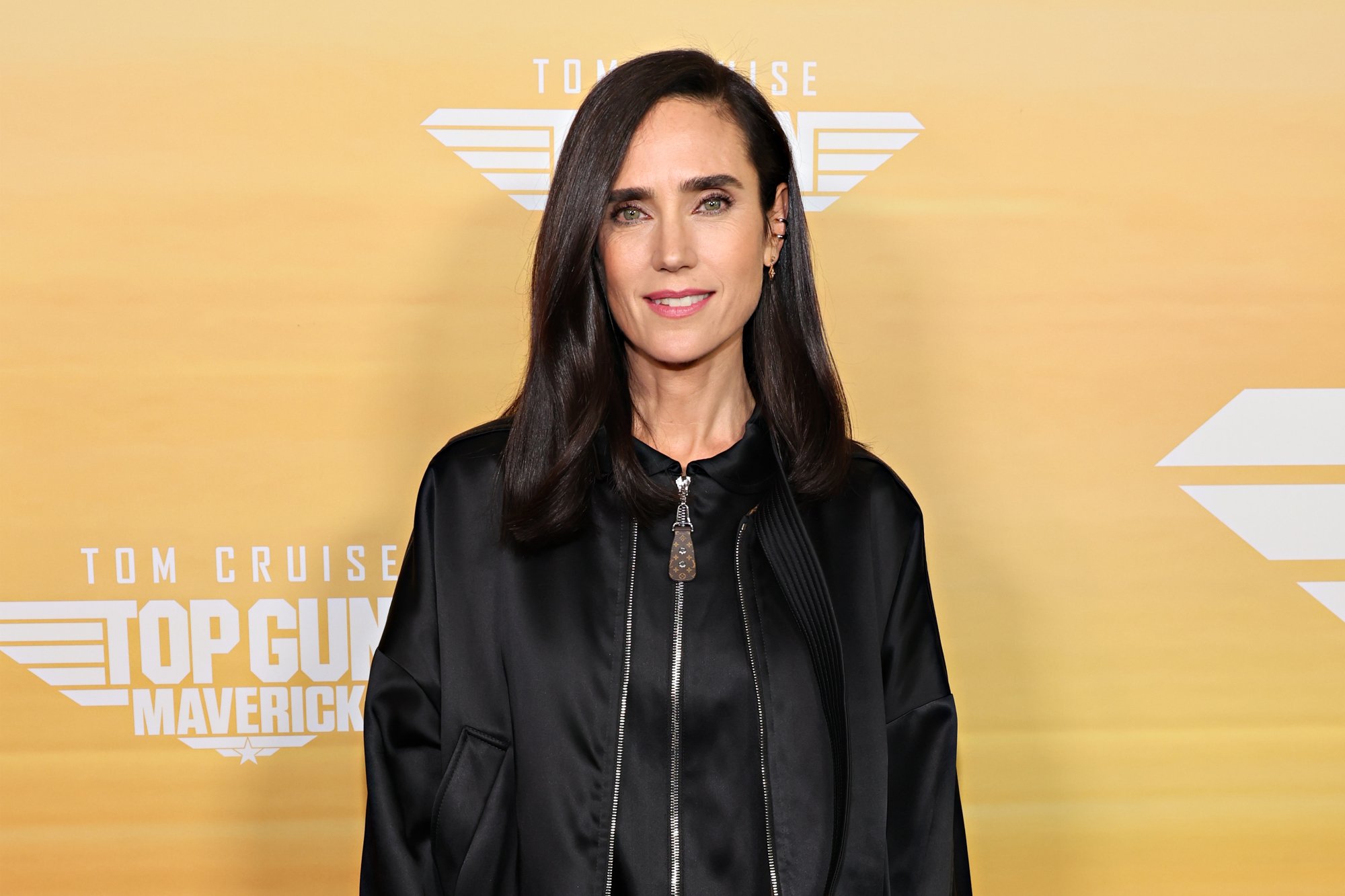 'Top Gun: Maverick' star Jennifer Connelly smiling and wearing all black in front of the movie step and repeat