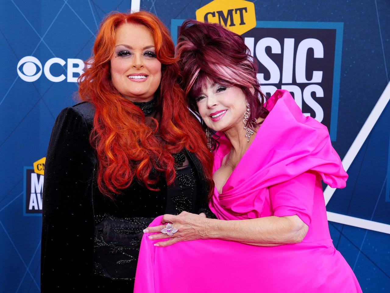 Wynonna Judd and Naomi Judd smile and pose close together