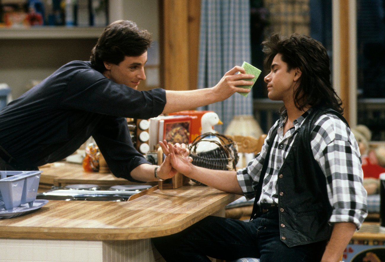 Danny (Bob Saget) wipes Jesse's (John Stamos) face with a sponge in an episode of 'Full House'