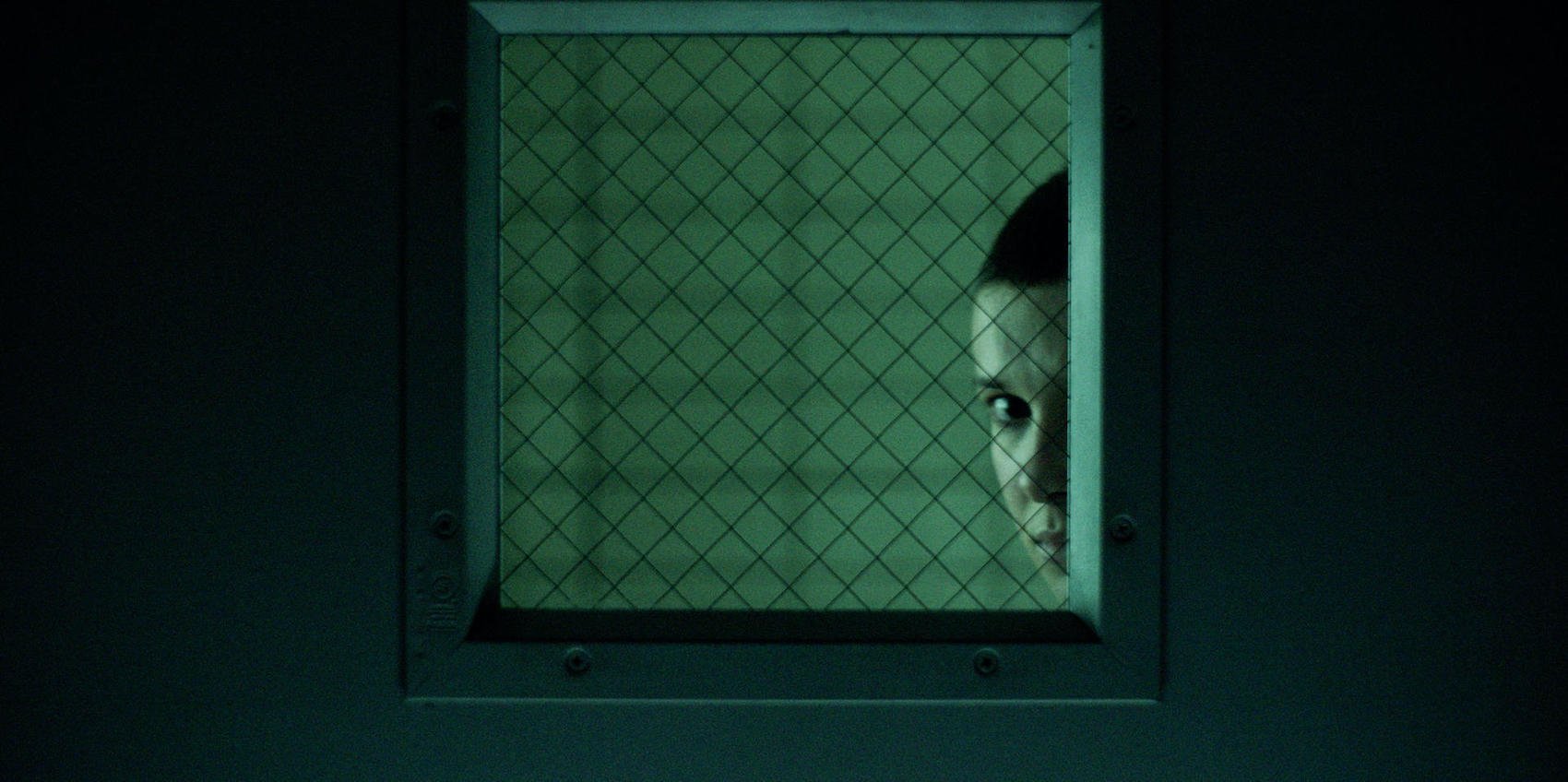 Young Eleven (Millie Bobby Brown) peers into a door at the Hawkins Lab in season 4 of 'Stranger Things'