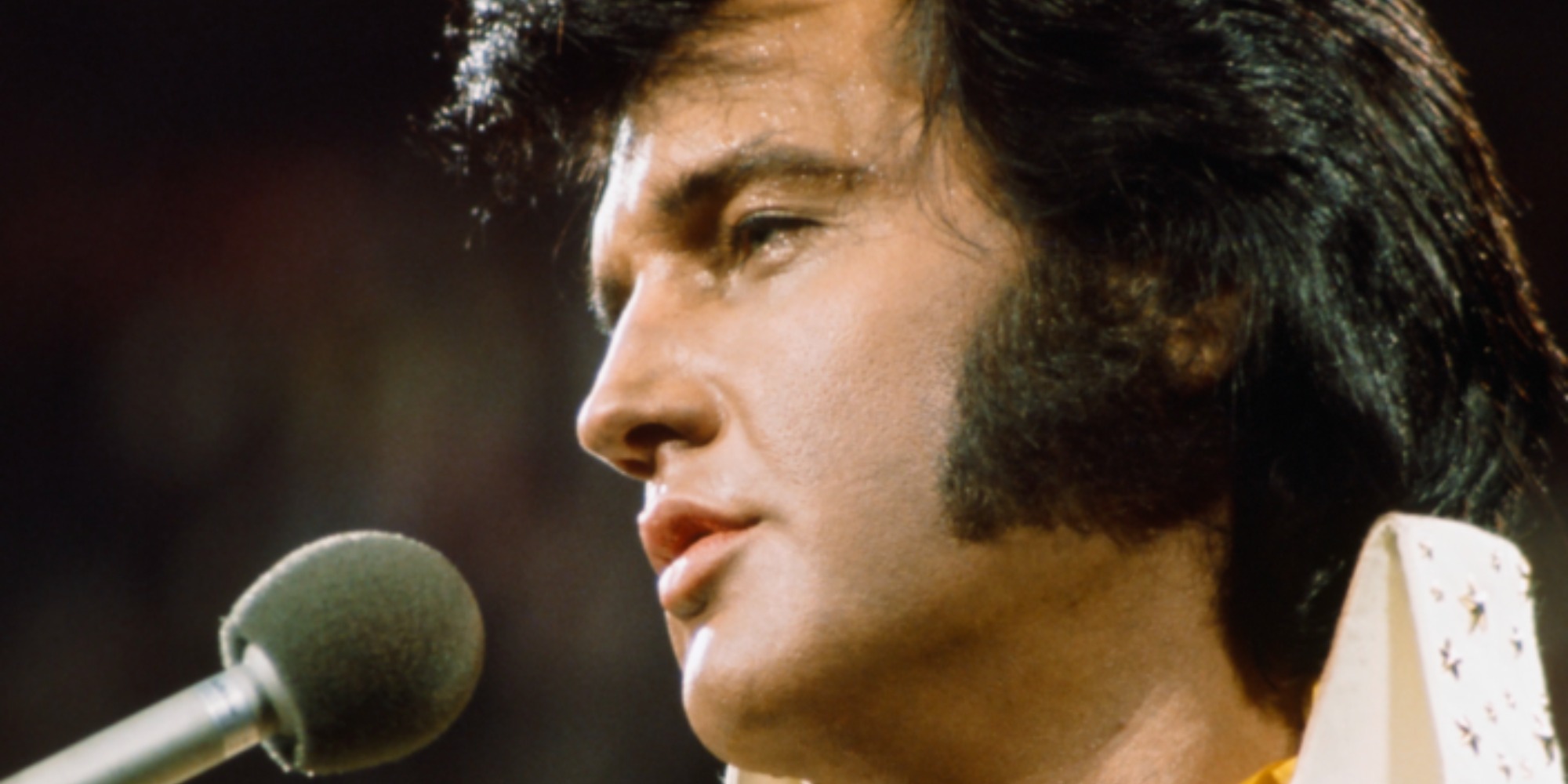 Elvis Presley chante dans un micro lors d'un concert.