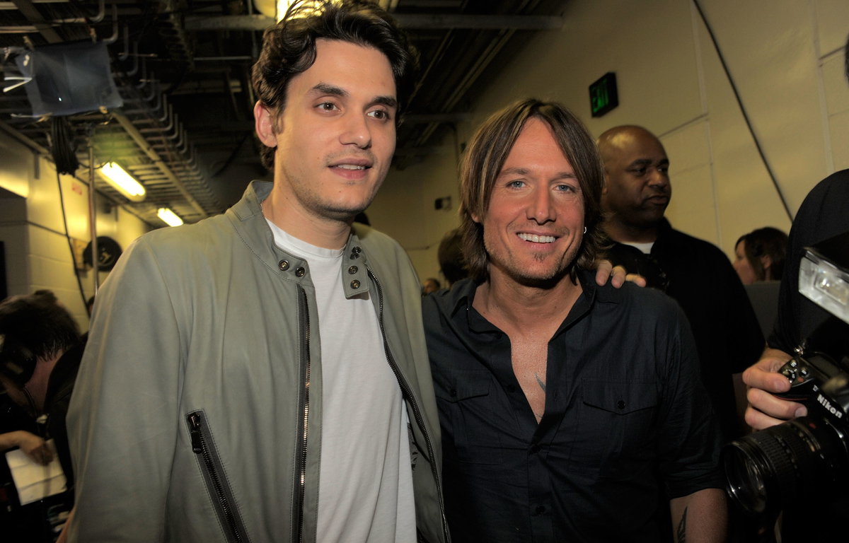 Keith Urban and John Mayer stand next to each other with thier arms on each other's shoulders.