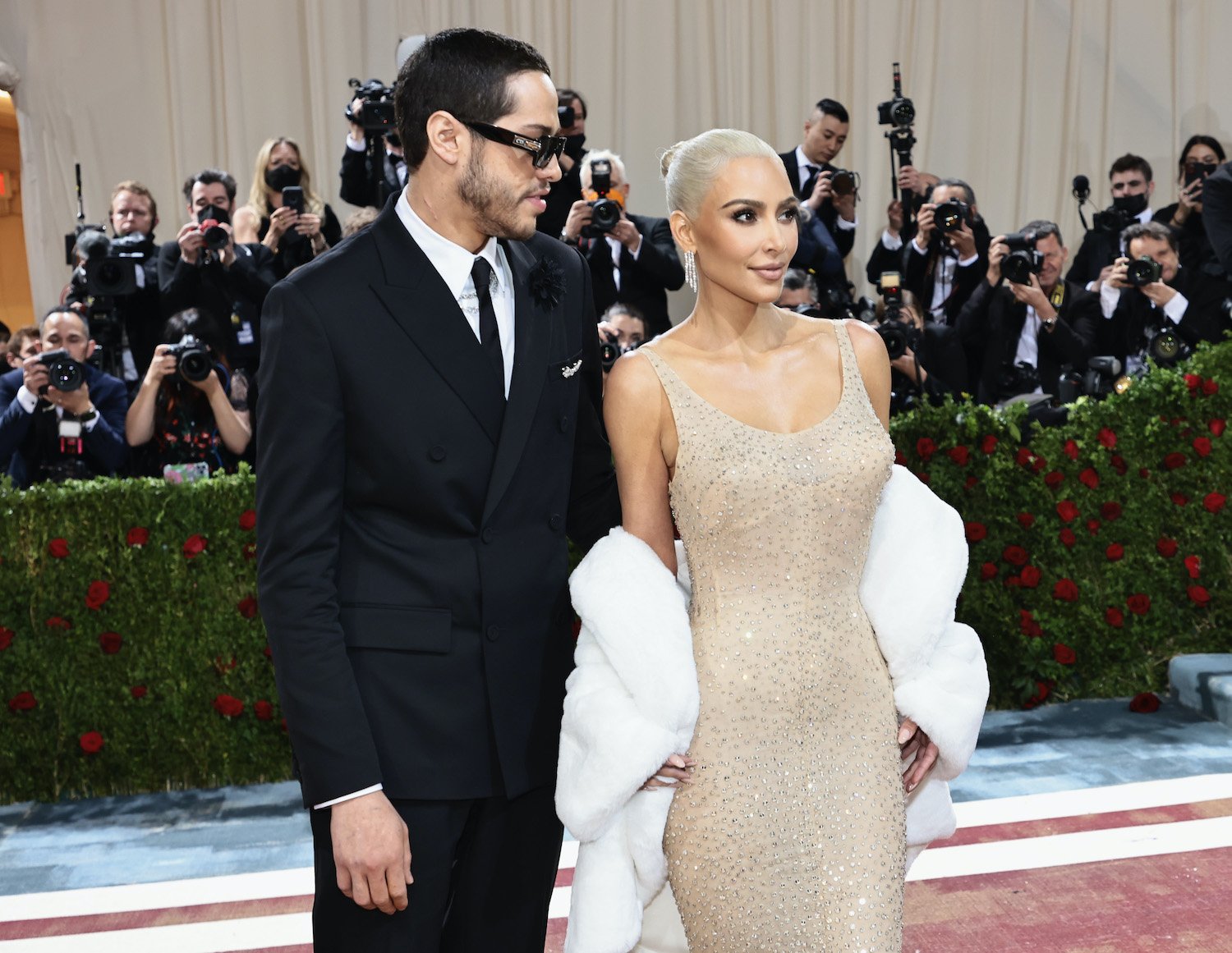 Kim Kardashian wears a nude colored sequin dress originally worn by Marilyn Monroe to the Met Gala 2022 with boyfriend Pete Davidson in a black suit and tie