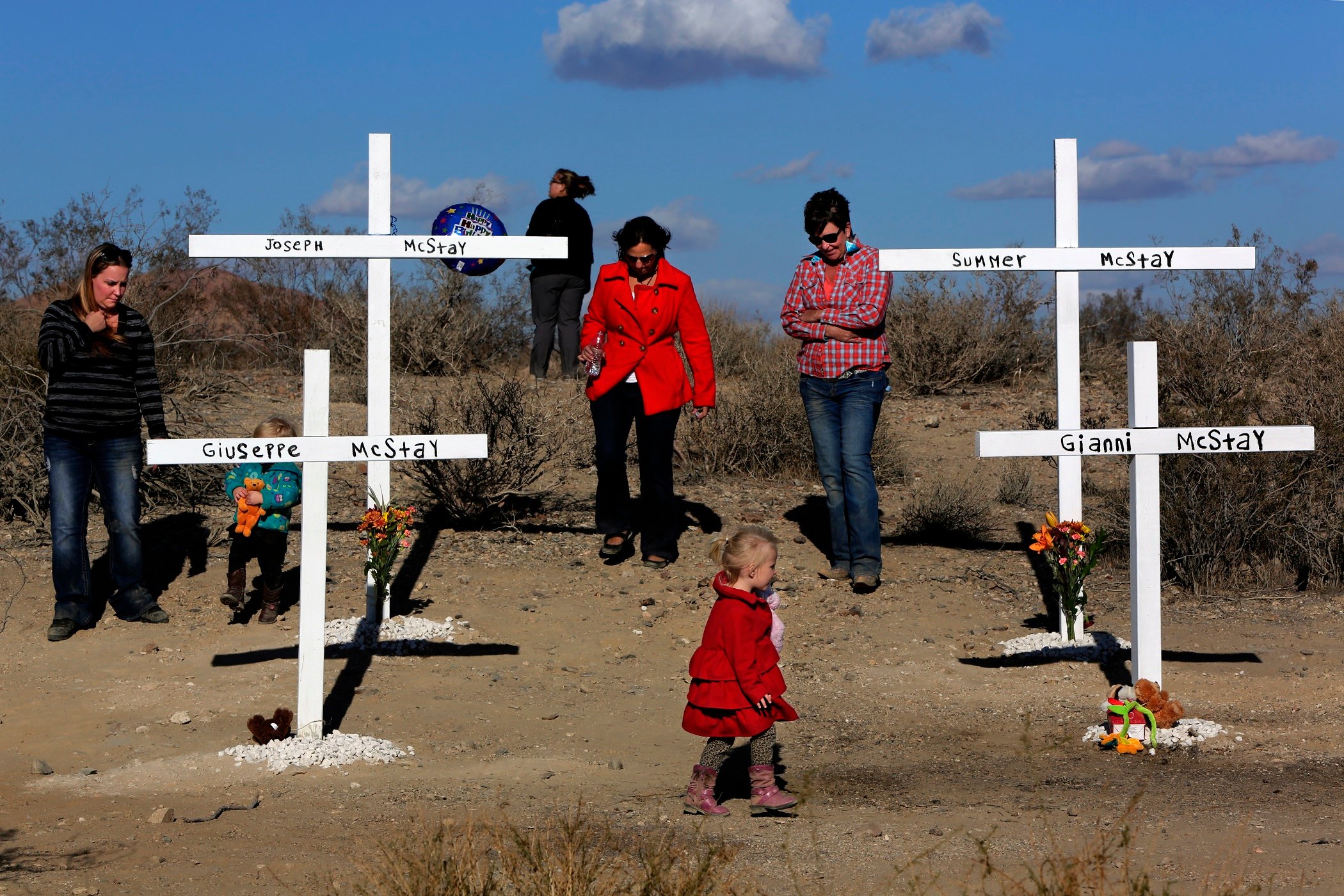 Family and friends gather at the site where Victor Valley News Group installed four crosses in the memory of the McStay family