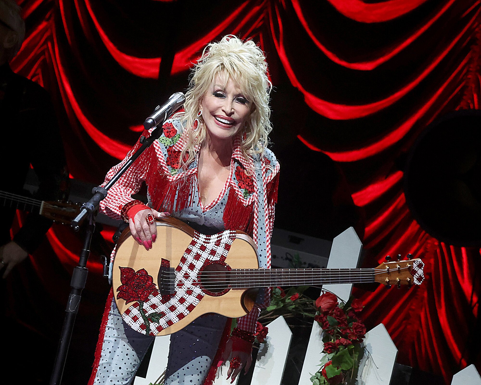 Dolly Parton, new Rock & Roll Hall of Fame inductee, performing on stage with guitar in hand.