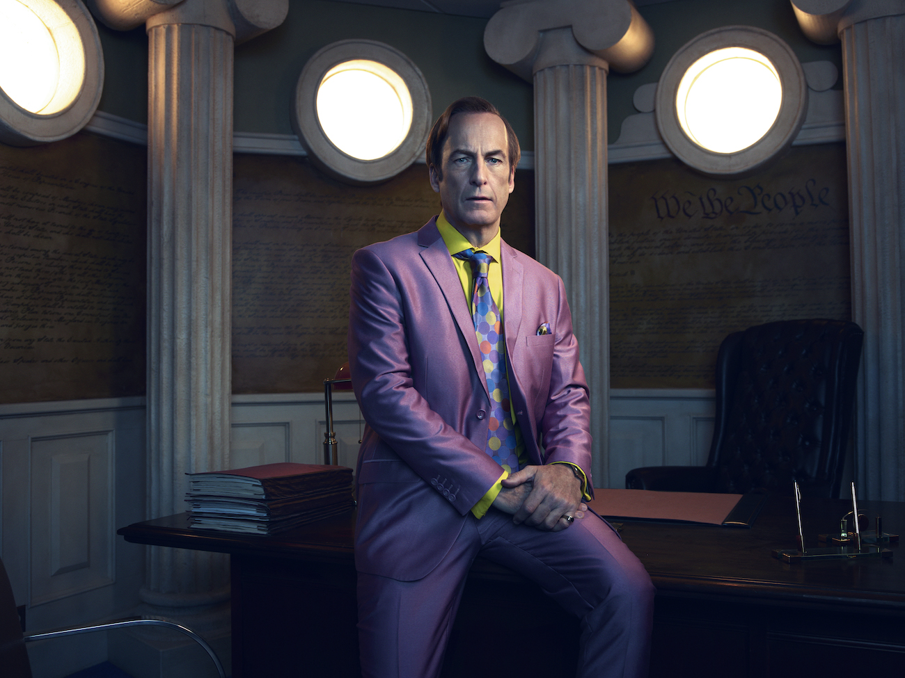Saul Goodman (Bob Odenkirk) sits on the desk of his office