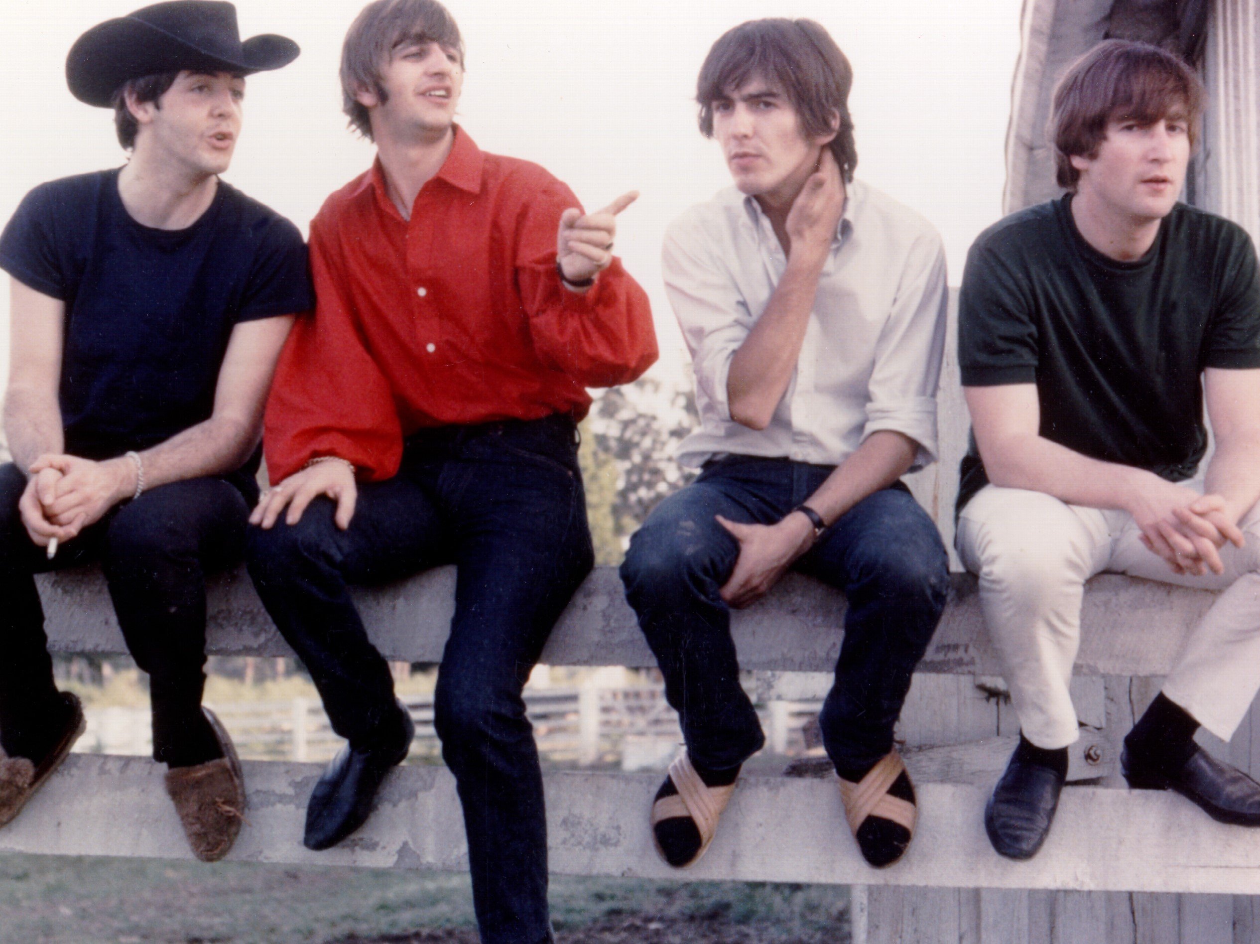 The Beatles' Paul McCartney, Ringo Starr, George Harrison, and John Lennon on a fence during the "I Saw Her Standing There"