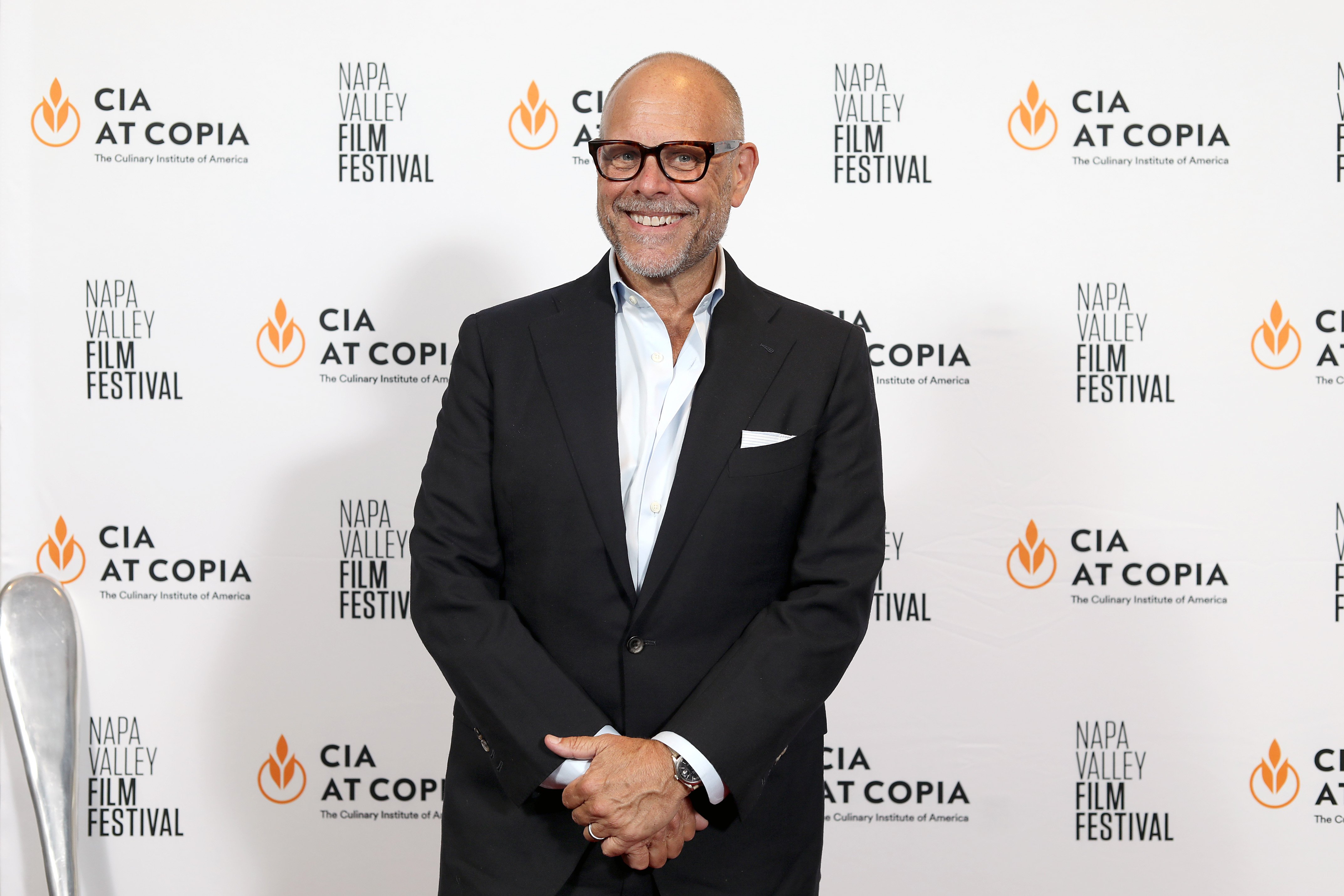 Celebrity chef Alton Brown poses for a photograph in a dark suit and white shirt.
