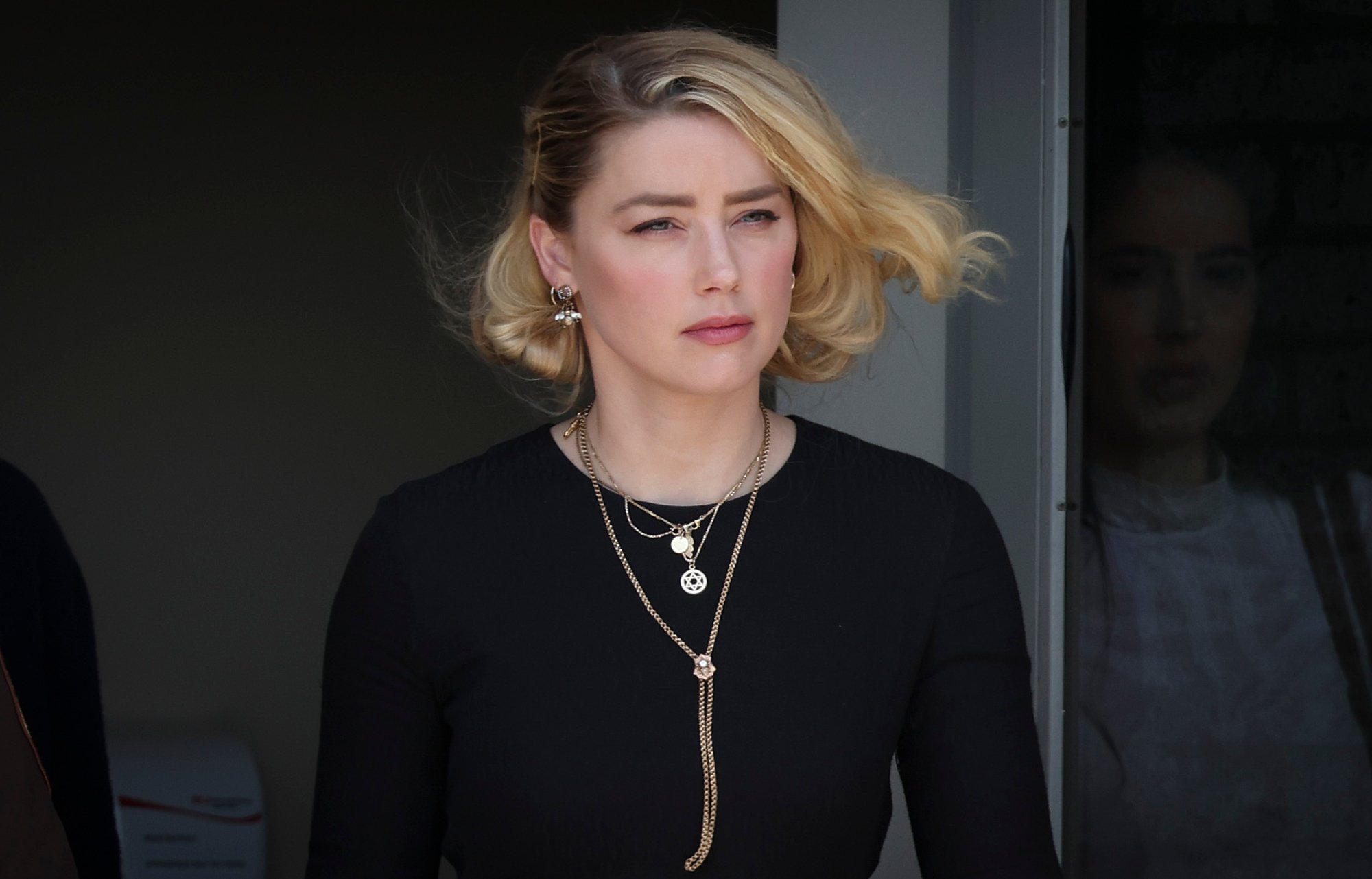 Amber Heard, who talked about free speech in her trial with Johnny Depp. She's wearing a long-sleeve black shirt and gold necklaces with her hair blowing in the wind.
