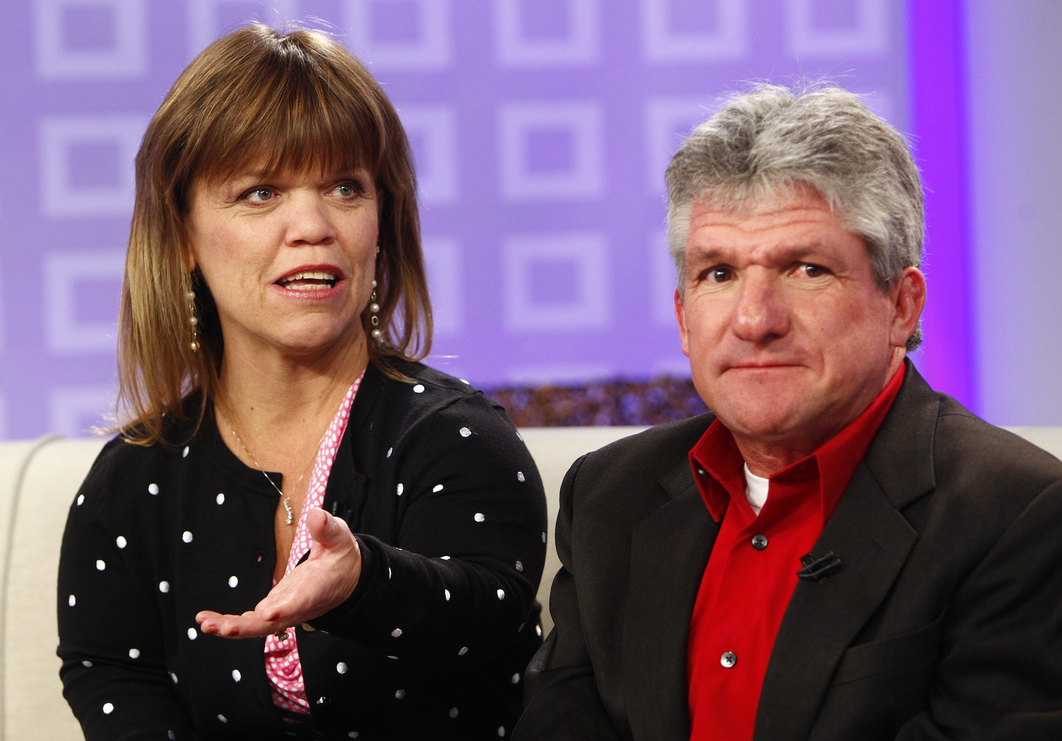 Amy Roloff and Matt Roloff from 'Little People, Big World' sitting together on a couch against a purple background