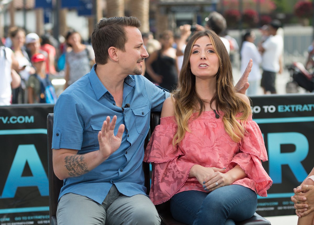 Evan Bass and Carly Waddell give an interview together during "Extra" at Universal Studios Hollywood