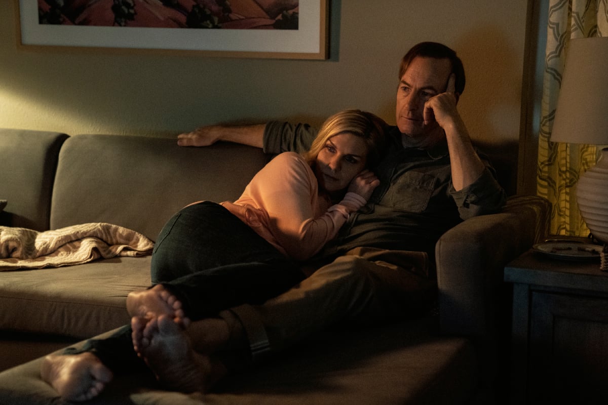 Bob Odenkirk as Saul Goodman and Rhea Seehorn as Kim Wexler in Better Call Saul Season 6. Kim and Jimmy cuddle on the couch. 