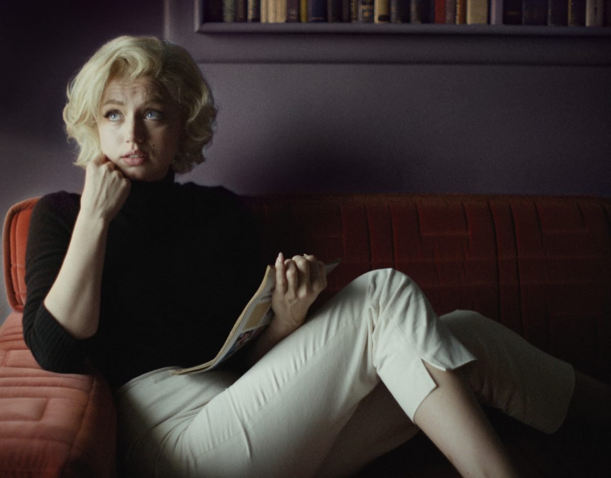 'Blonde' Ana de Armas dans le rôle de Marilyn Monroe assise sur un canapé lisant un morceau de papier