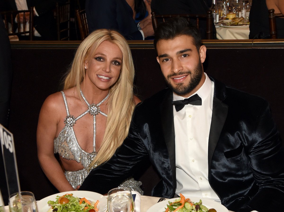 Britney Spears and Sam Asghari, who reportedly have a wedding on June 9, smile while sitting at a table