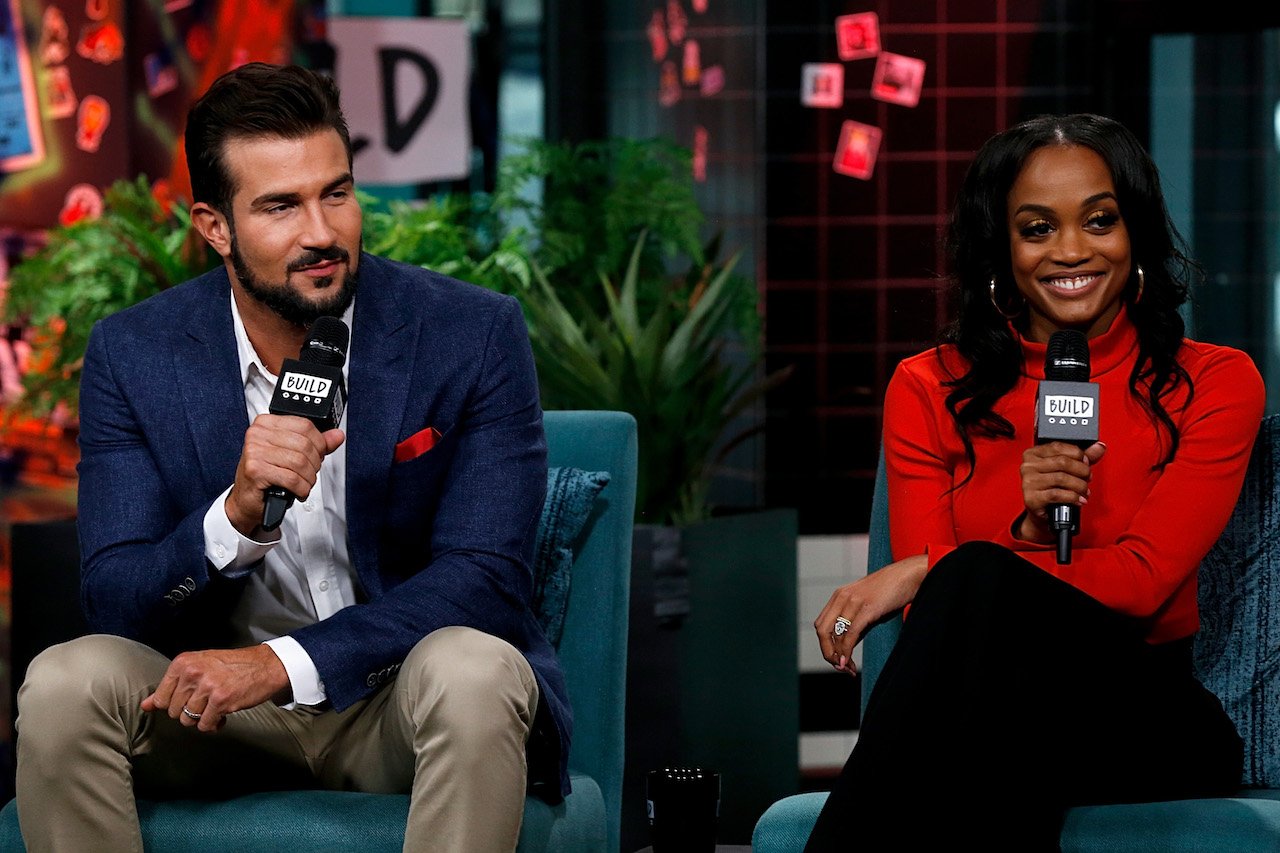 Bryan Abasolo and Rachel Lindsay sit next to each other on a stage holding microphones.
