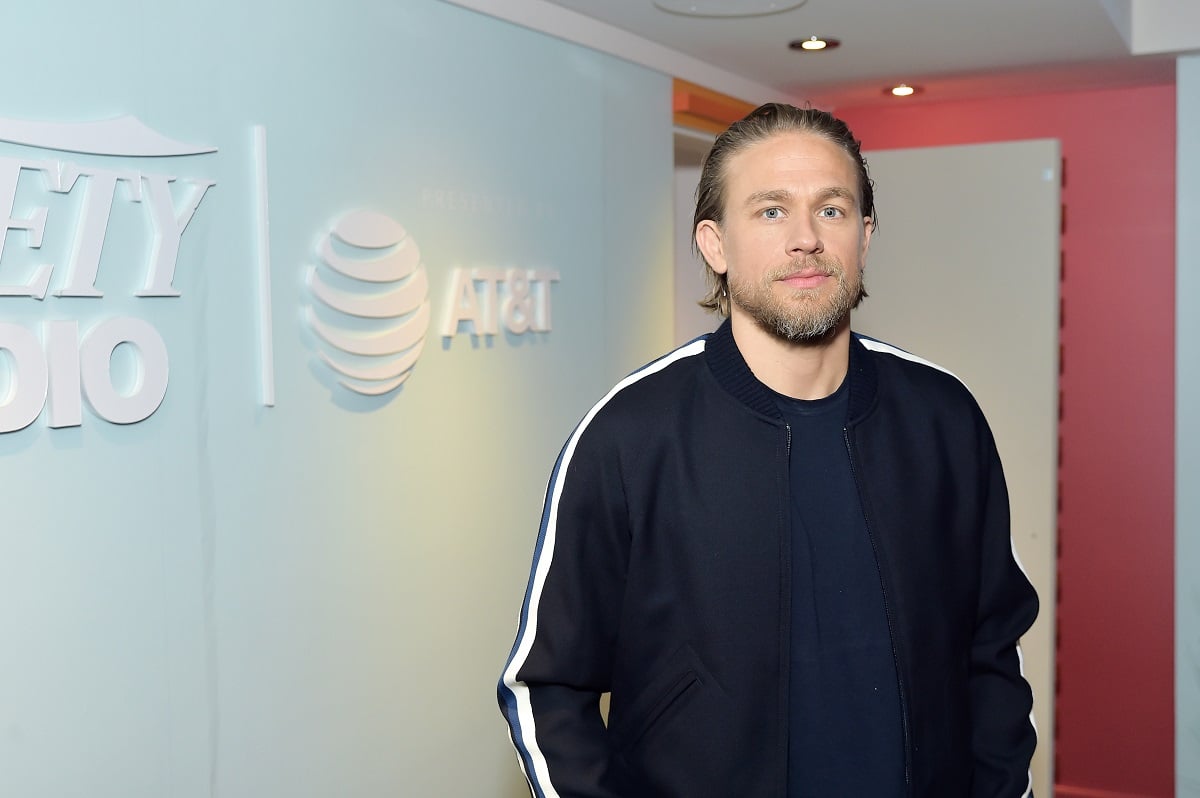 Charlie Hunnam posing while wearing a black and white jacket.
