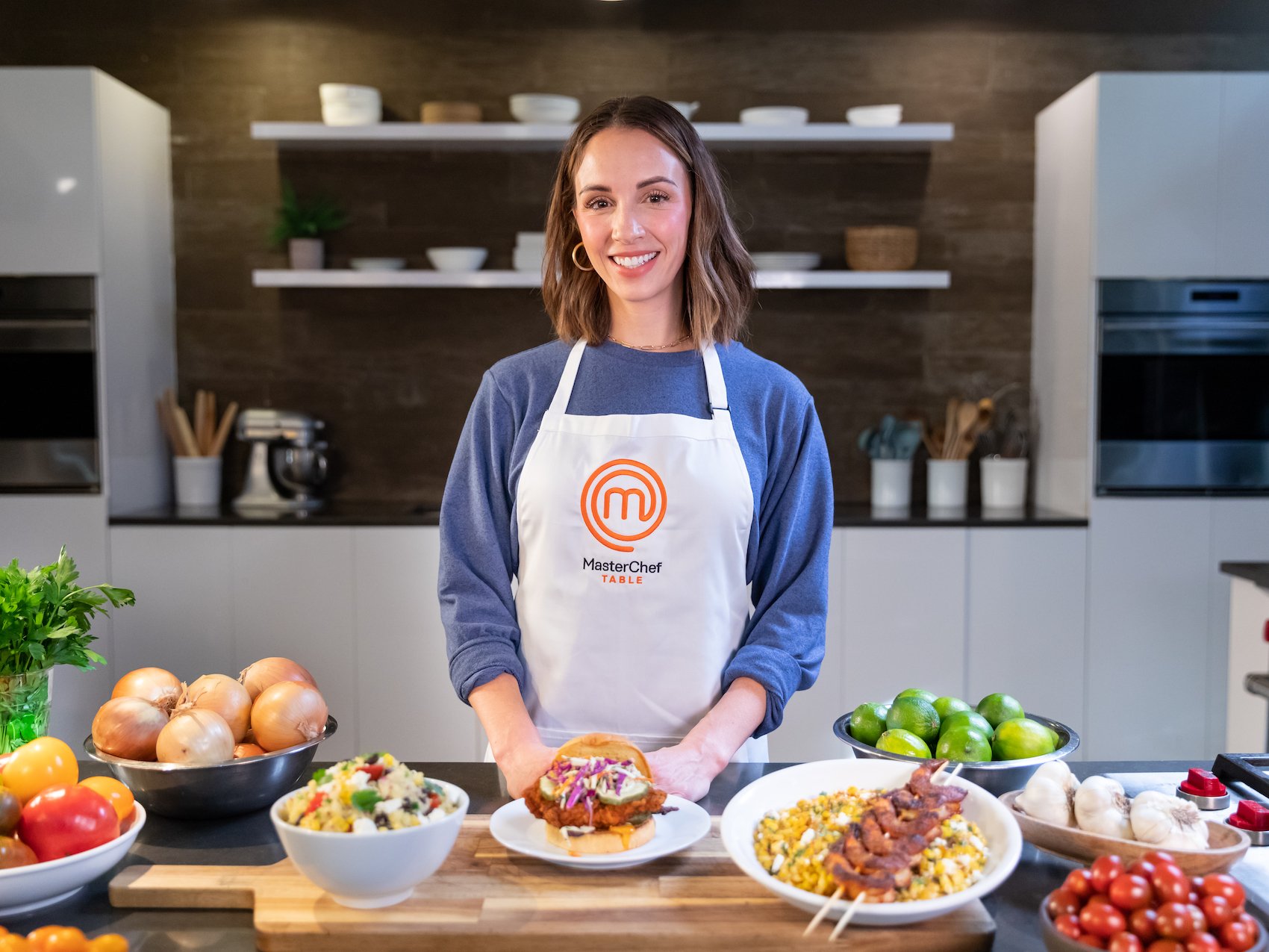 MasterChef Kelsey Murphy stands behind a table filled with food 
