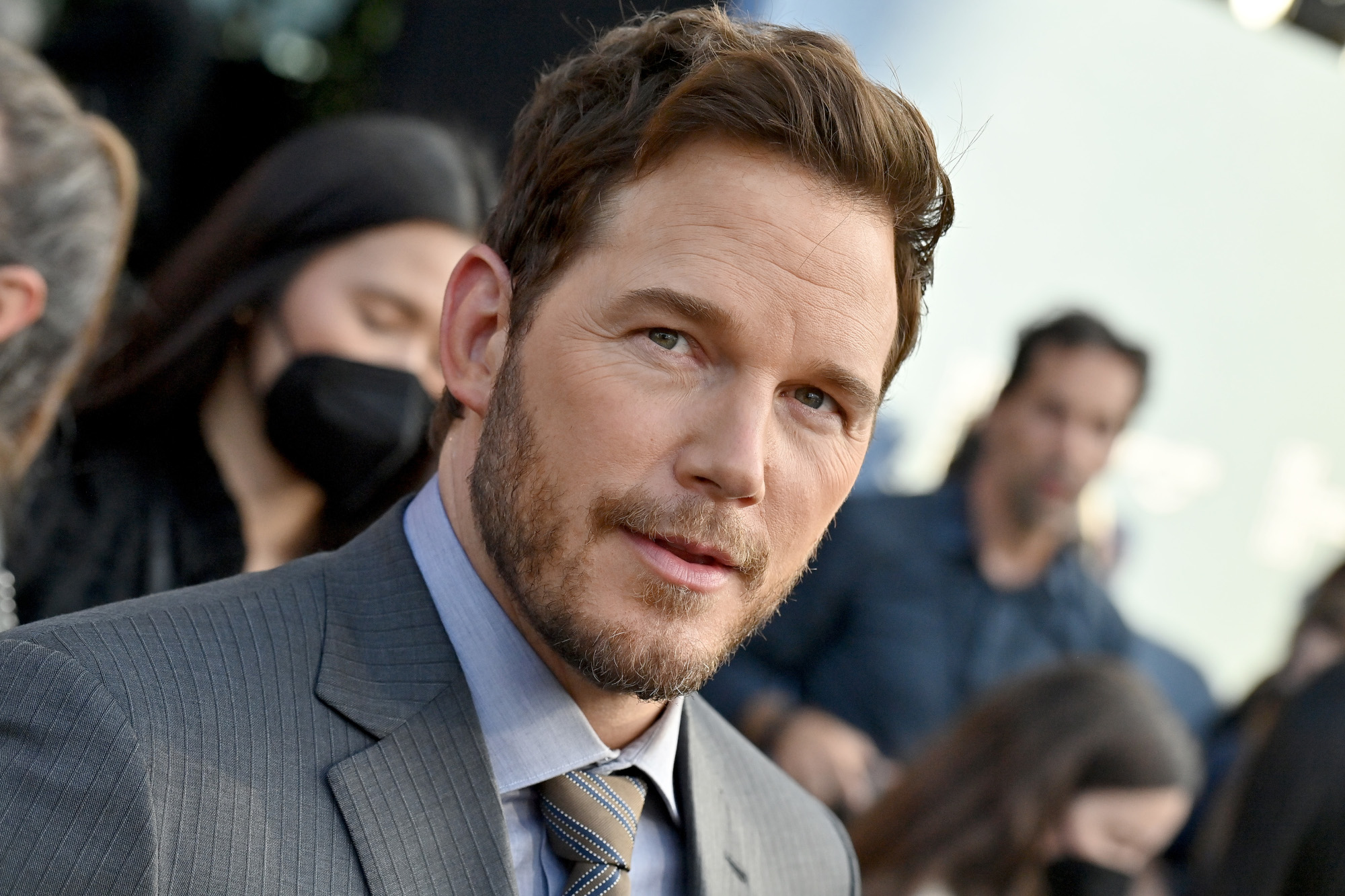 Chris Pratt, who will voice Mario in the upcoming 'Super Mario Bros.' adaptation. He's wearing a light blue shirt and gray suit.