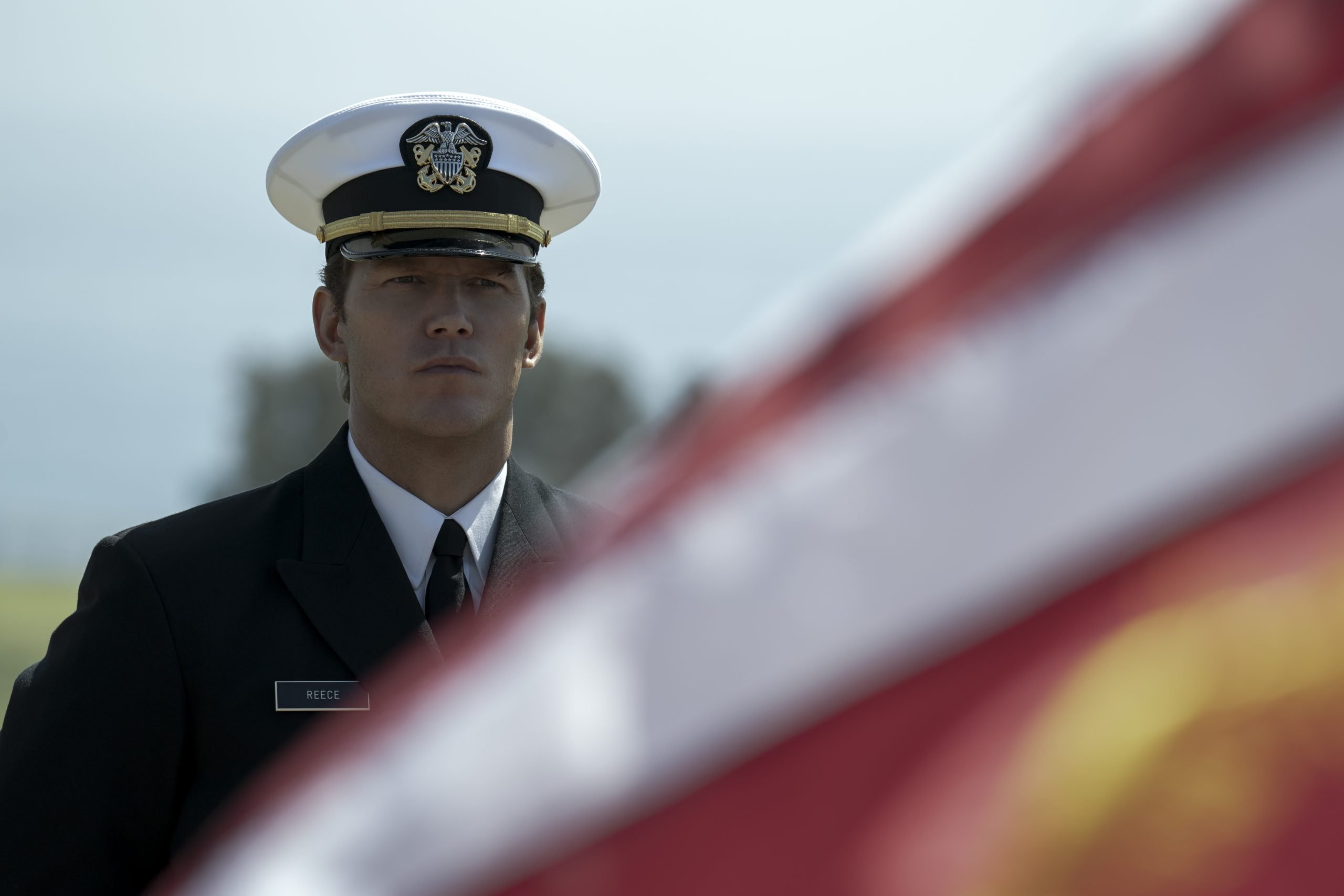 Chris Pratt in military uniform standing in front of an out-of-focus flag in 'The Terminal List'