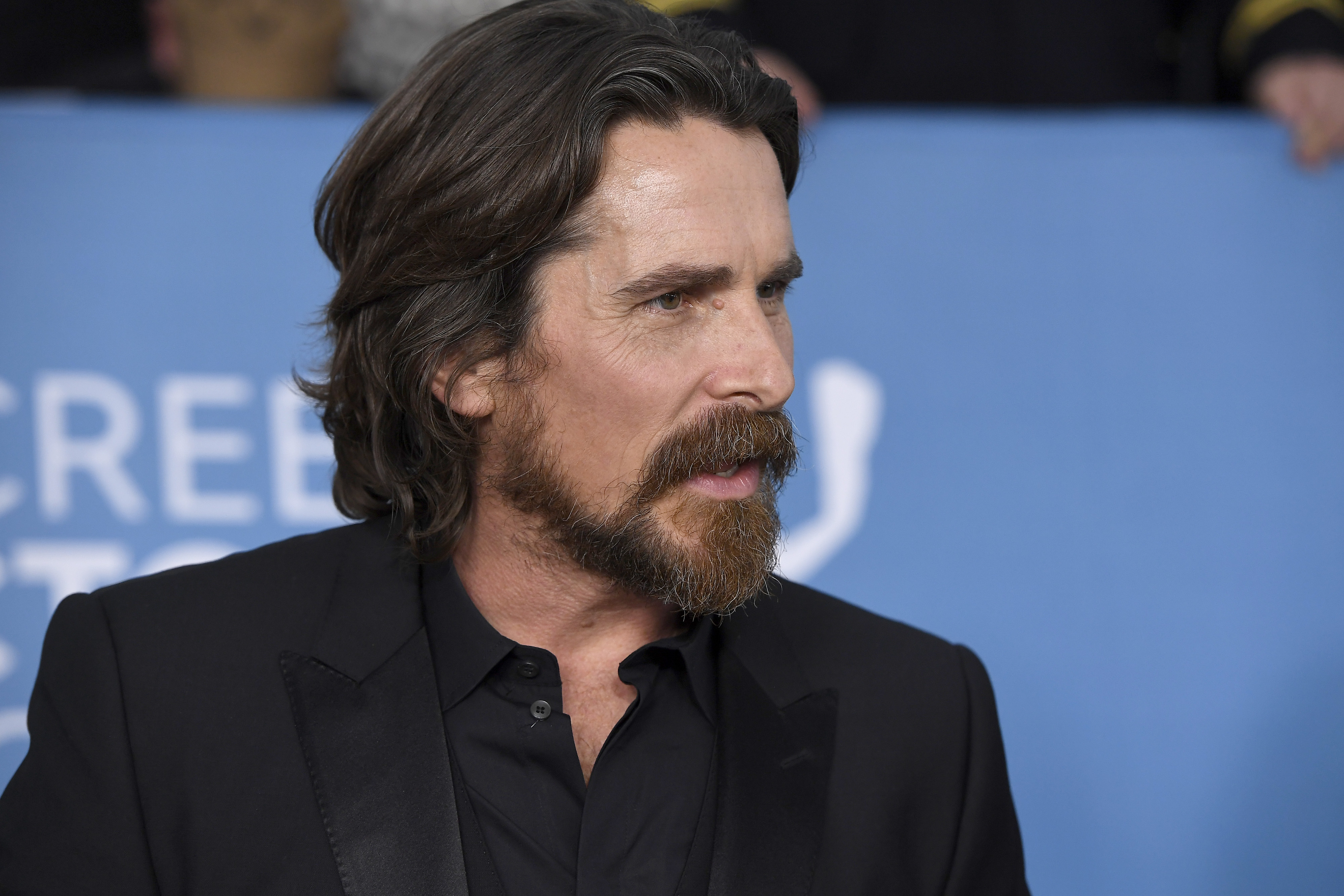 Christian Bale, who stars as Gorr the God Butcher in 'Thor: Love and Thunder,' wears a black suit over a black button-up shirt.