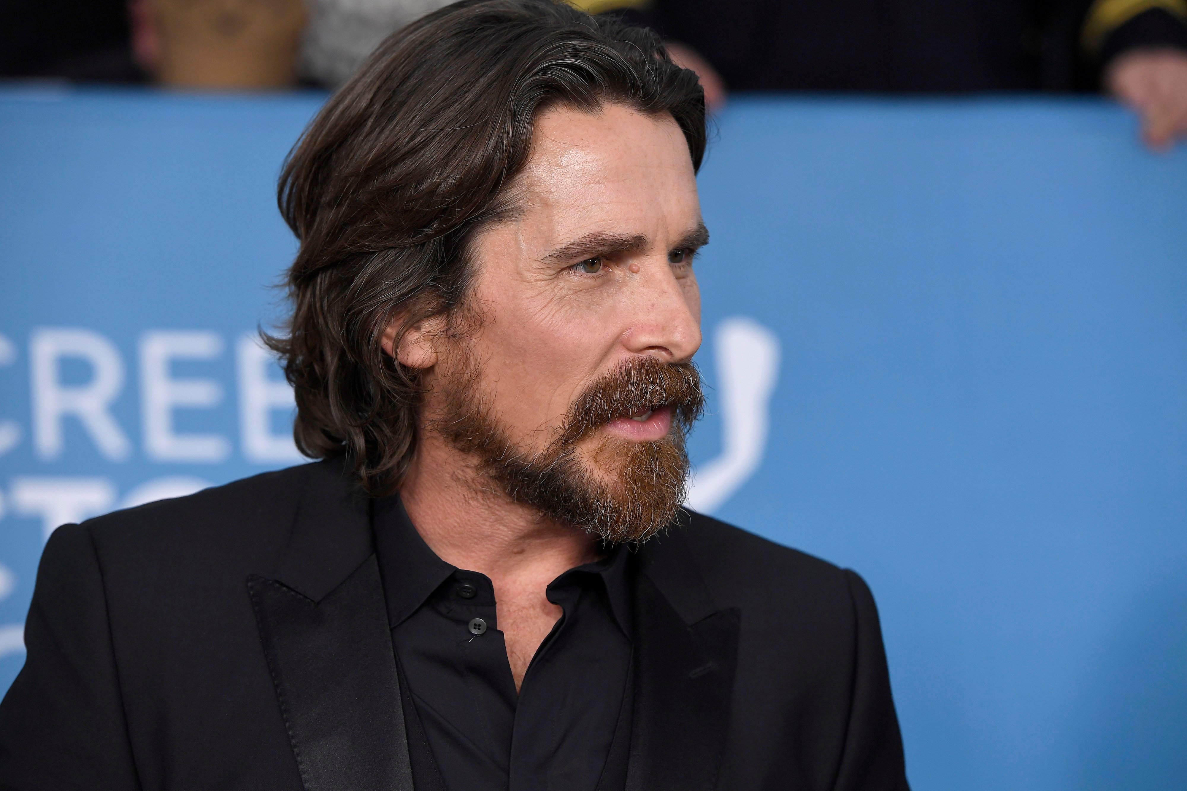 Christian Bale, who stars as Gorr the God Butcher in 'Thor: Love and Thunder,' wears a black suit over a black button-up shirt.