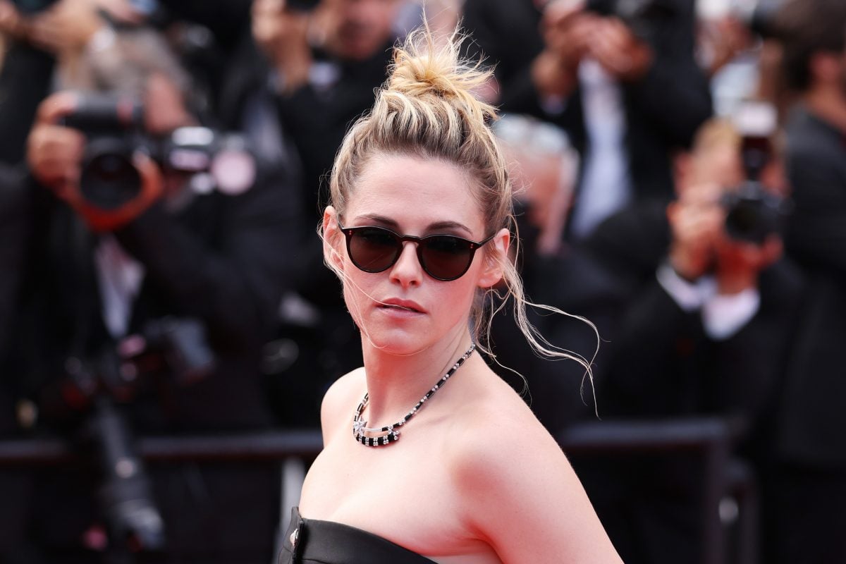 'Crimes of the Future' actor Kristen Stewart wearing sunglasses with her hair up. Photographers are in the background.