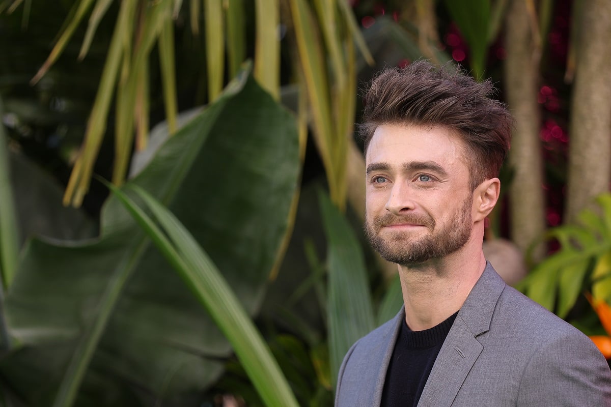 Daniel Radcliffe posing while wearing a grey suit.
