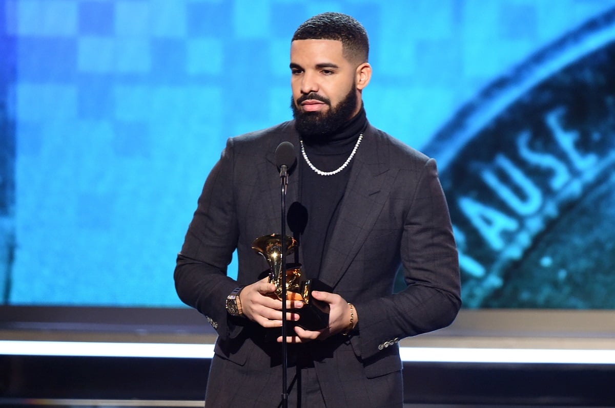 Drake accepting Grammy award while wearing a black suit.