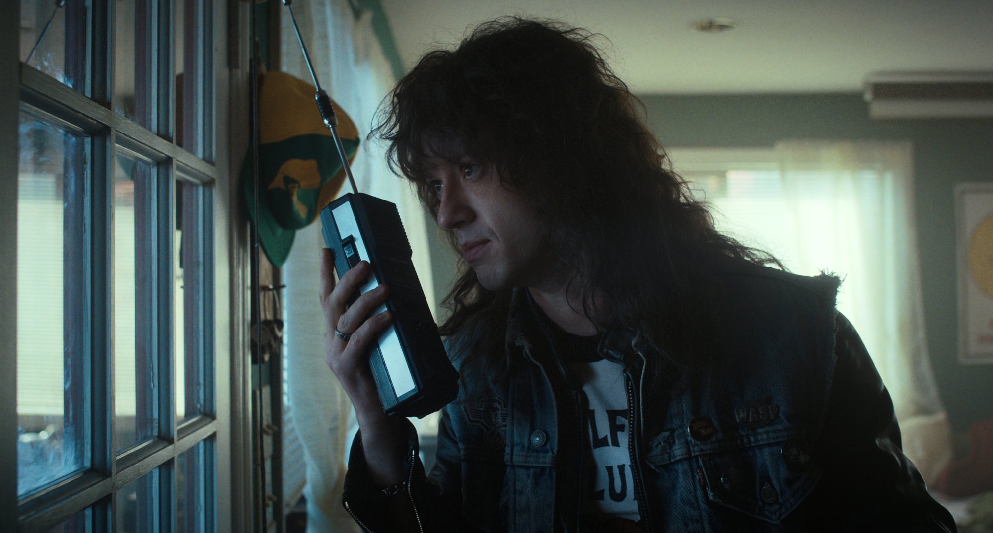Eddie Munson using walkie-talkie while wearing DIO jean jacket in 'Stranger Things' Season 4