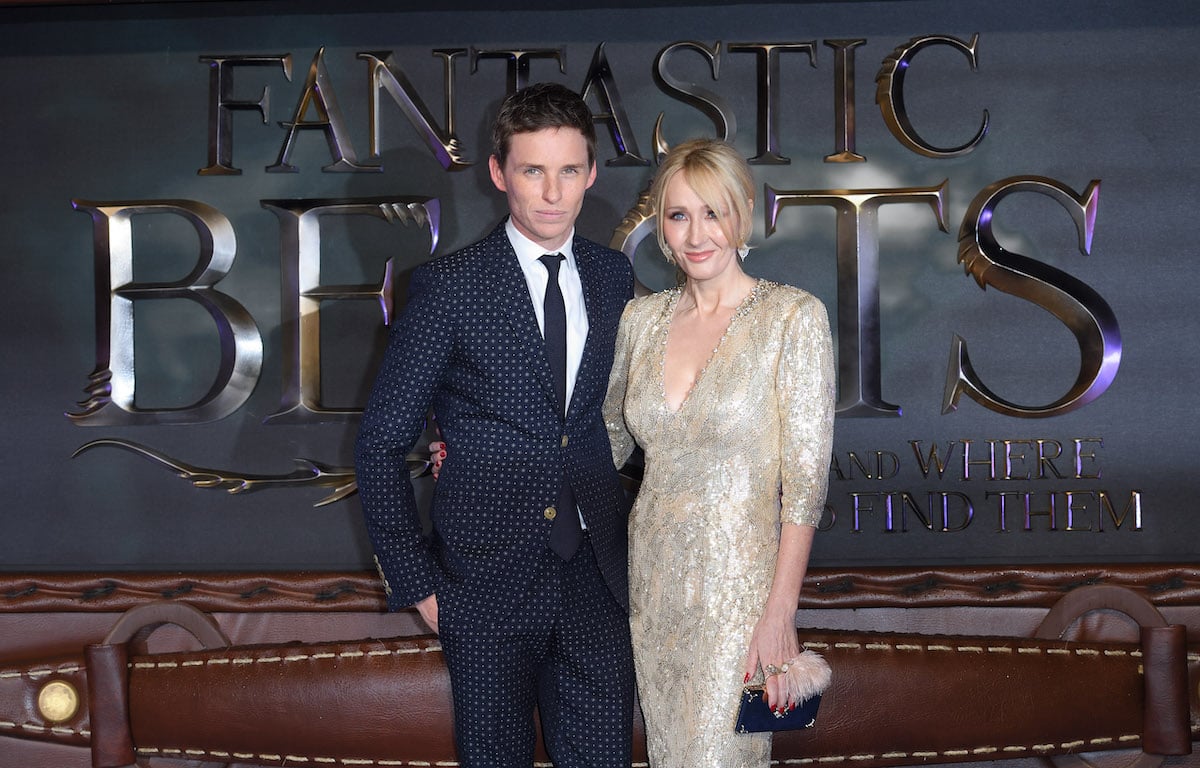 Eddie Redmayne and J. K. Rowling stand arm in arm at the premiere of "Fantastic Beasts And Where To Find Them" in 2016