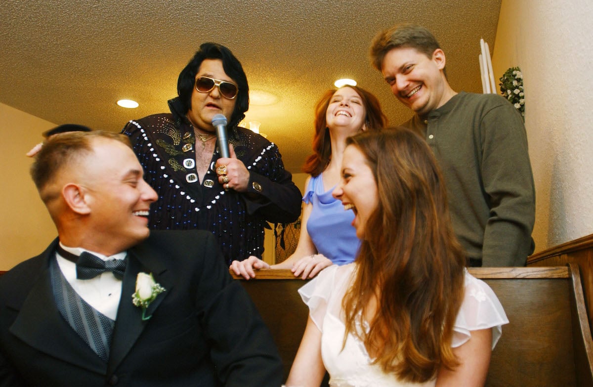 A newly married couple laughs with an Elvis Presley impersonator at Graceland wedding chapel in Las Vegas